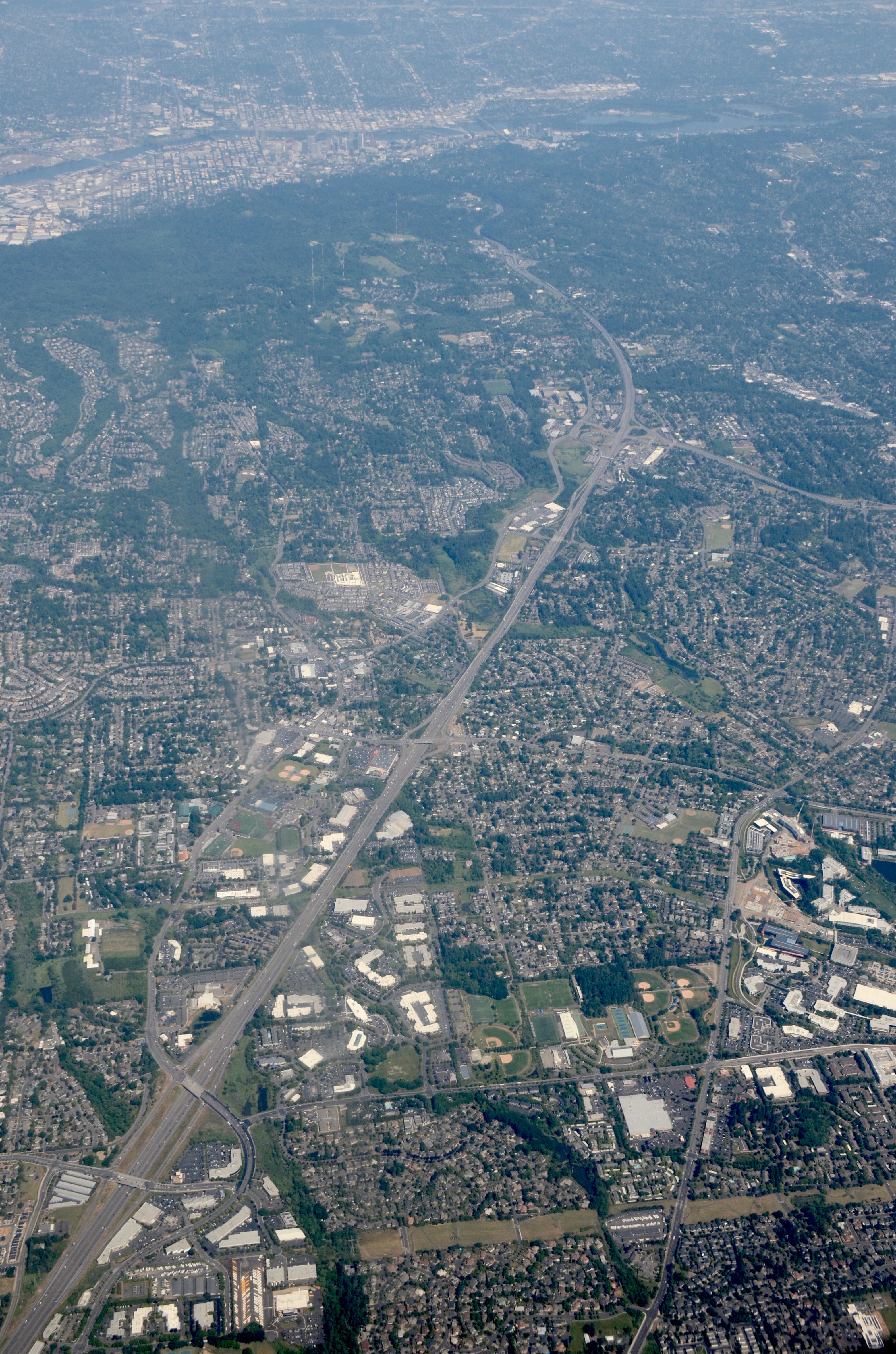 Aerial view of a freeway corridor through suburban neighborhoods with road overpasses visible.