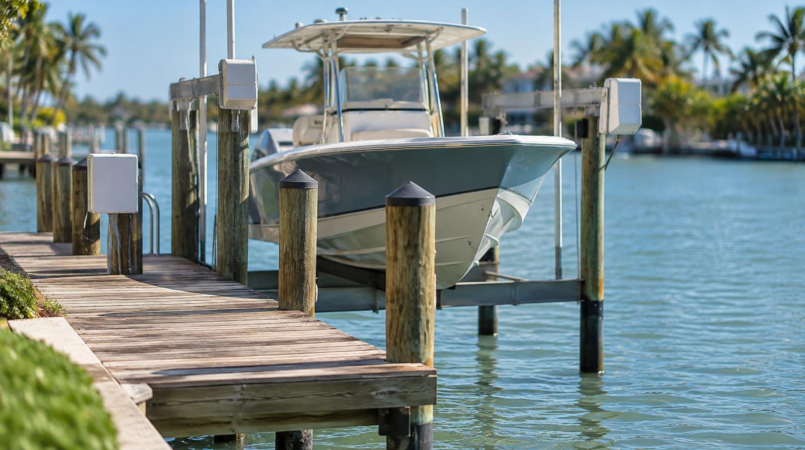 A wooden dock with a boat lift extending over calm blue-green water.