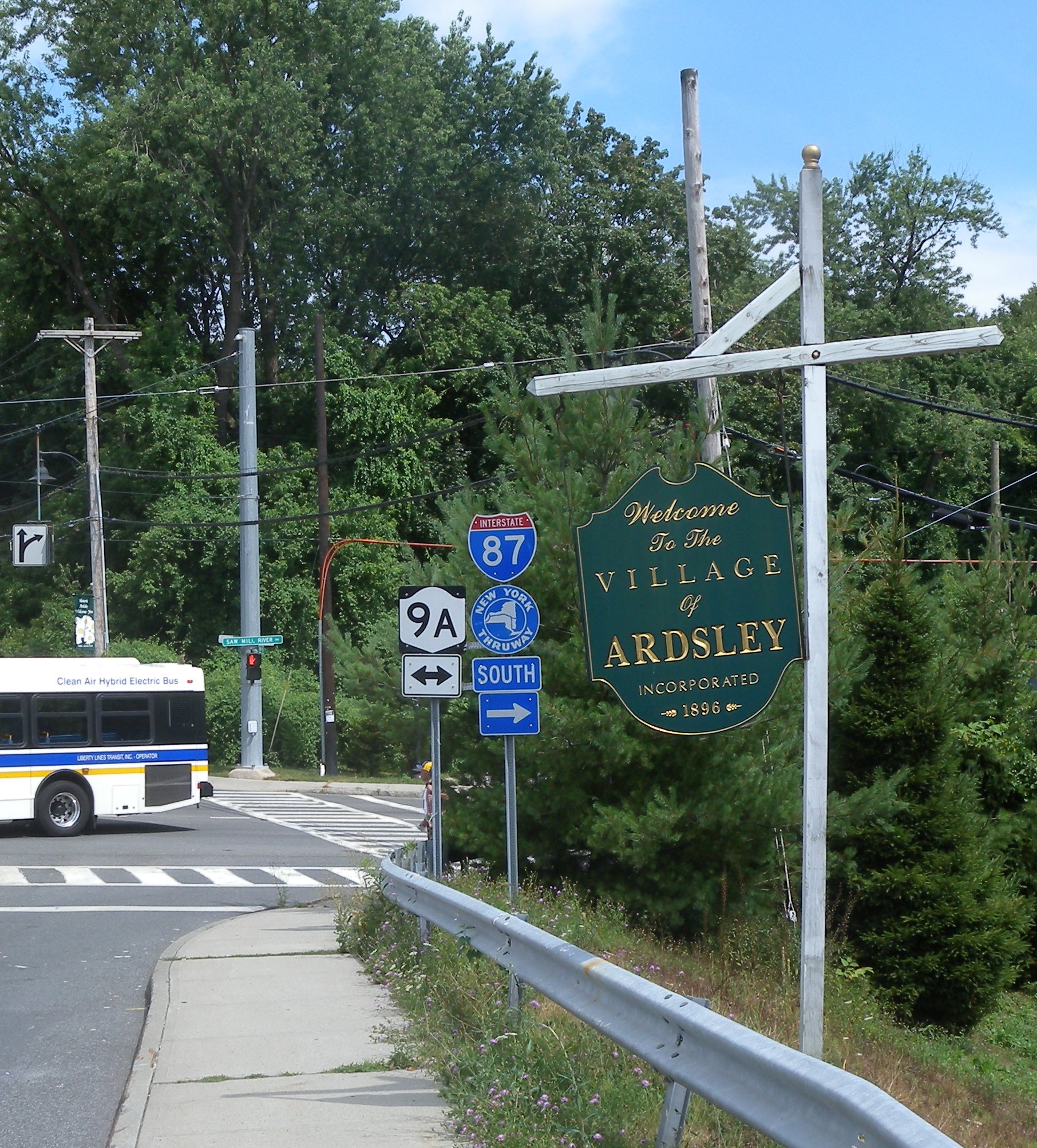 Welcome to the Village of Ardsley sign alongside highway signs on a sunny day.