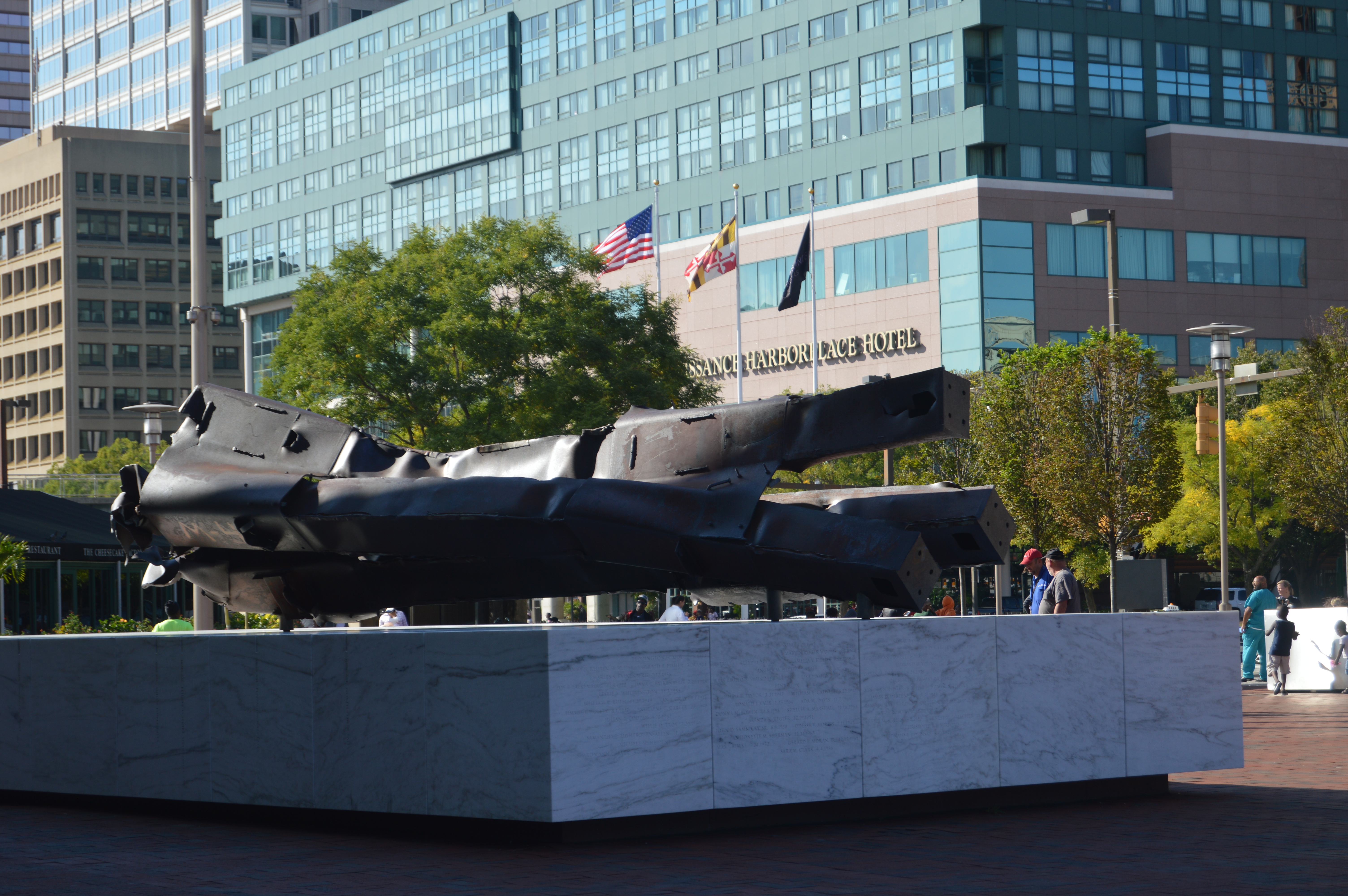 Large dark steel beams from the World Trade Center on a white marble memorial base.