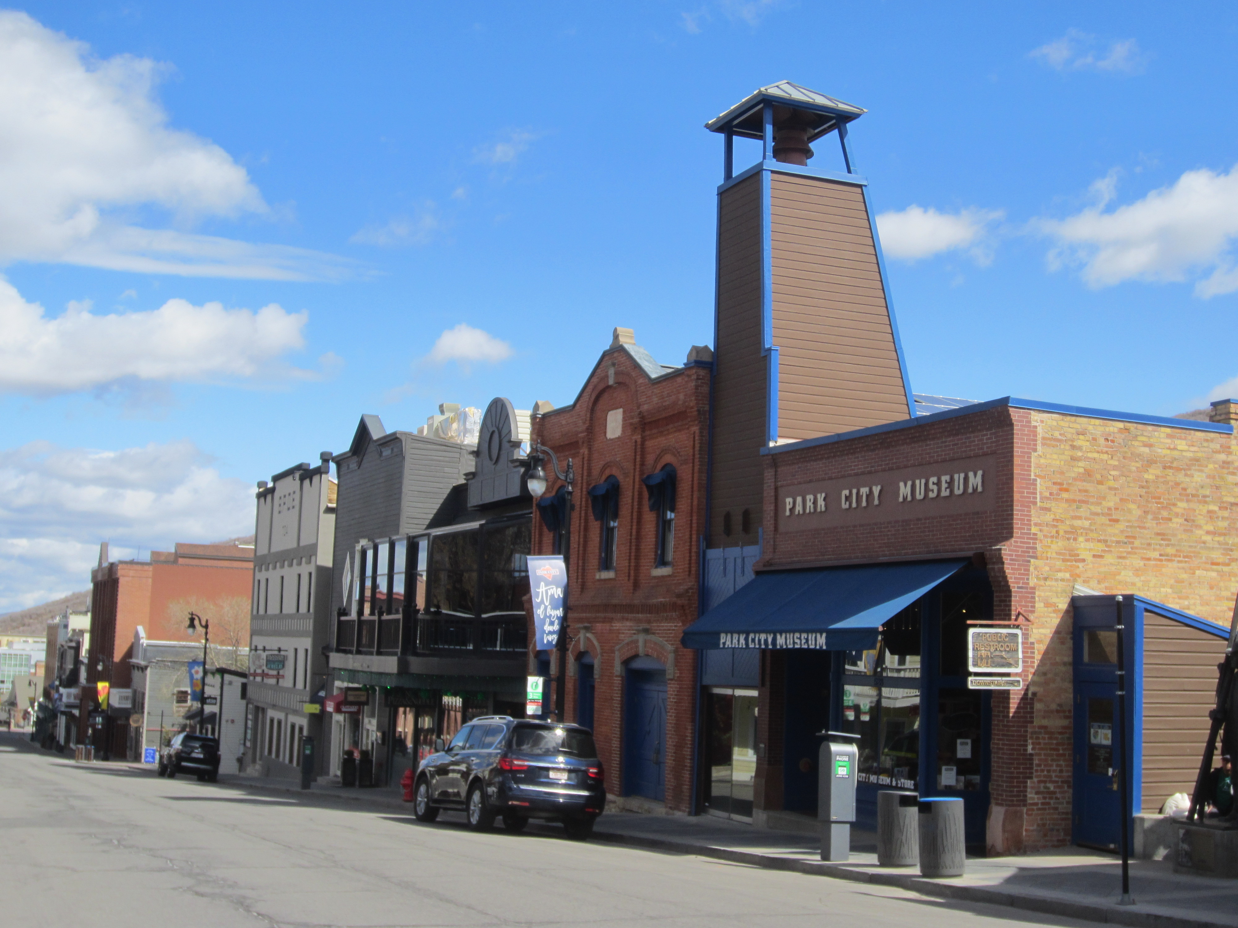 Brick museum building on a main street with blue awnings and a tower.