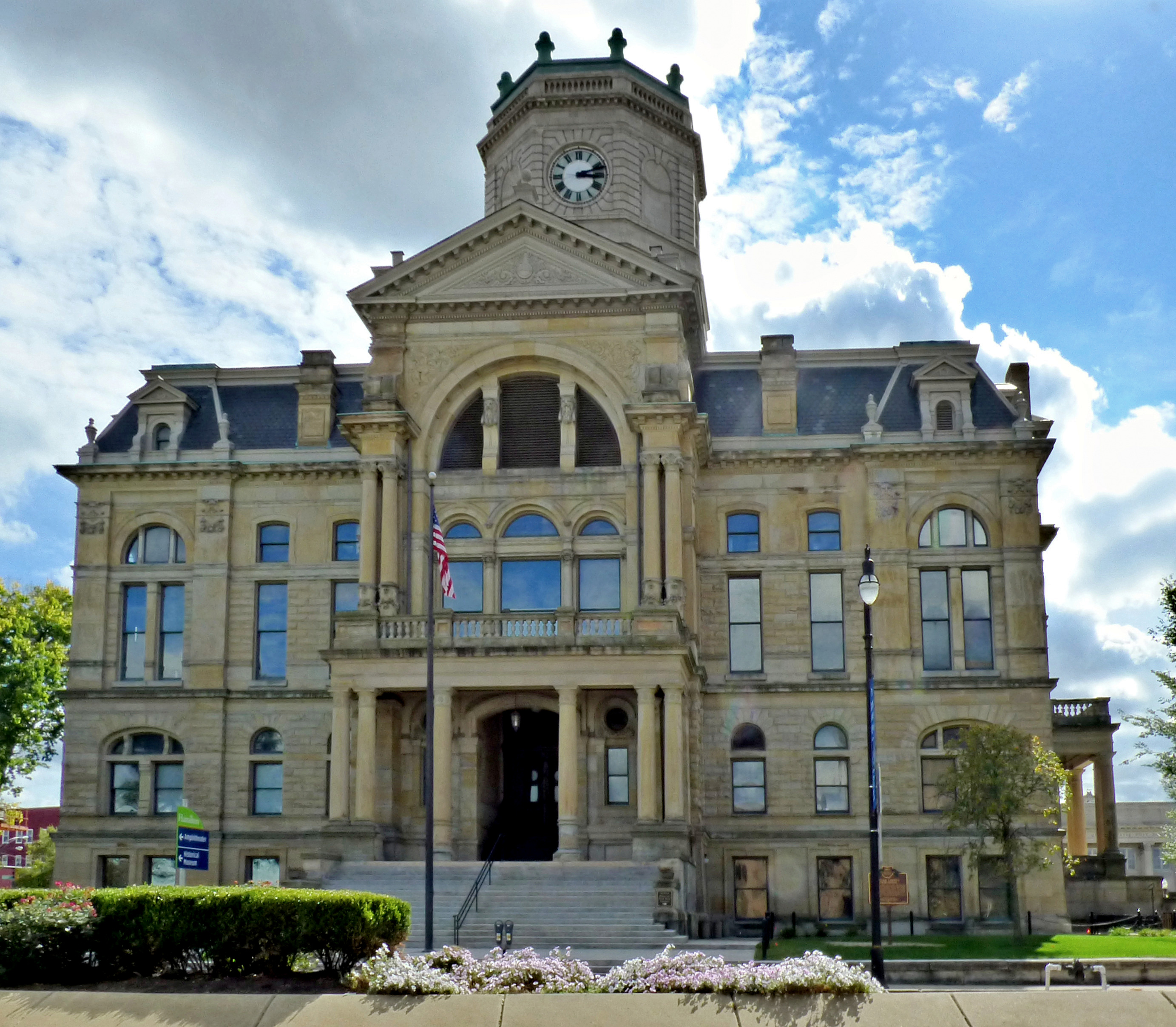 Ornate stone courthouse building with central clock tower and American flag.