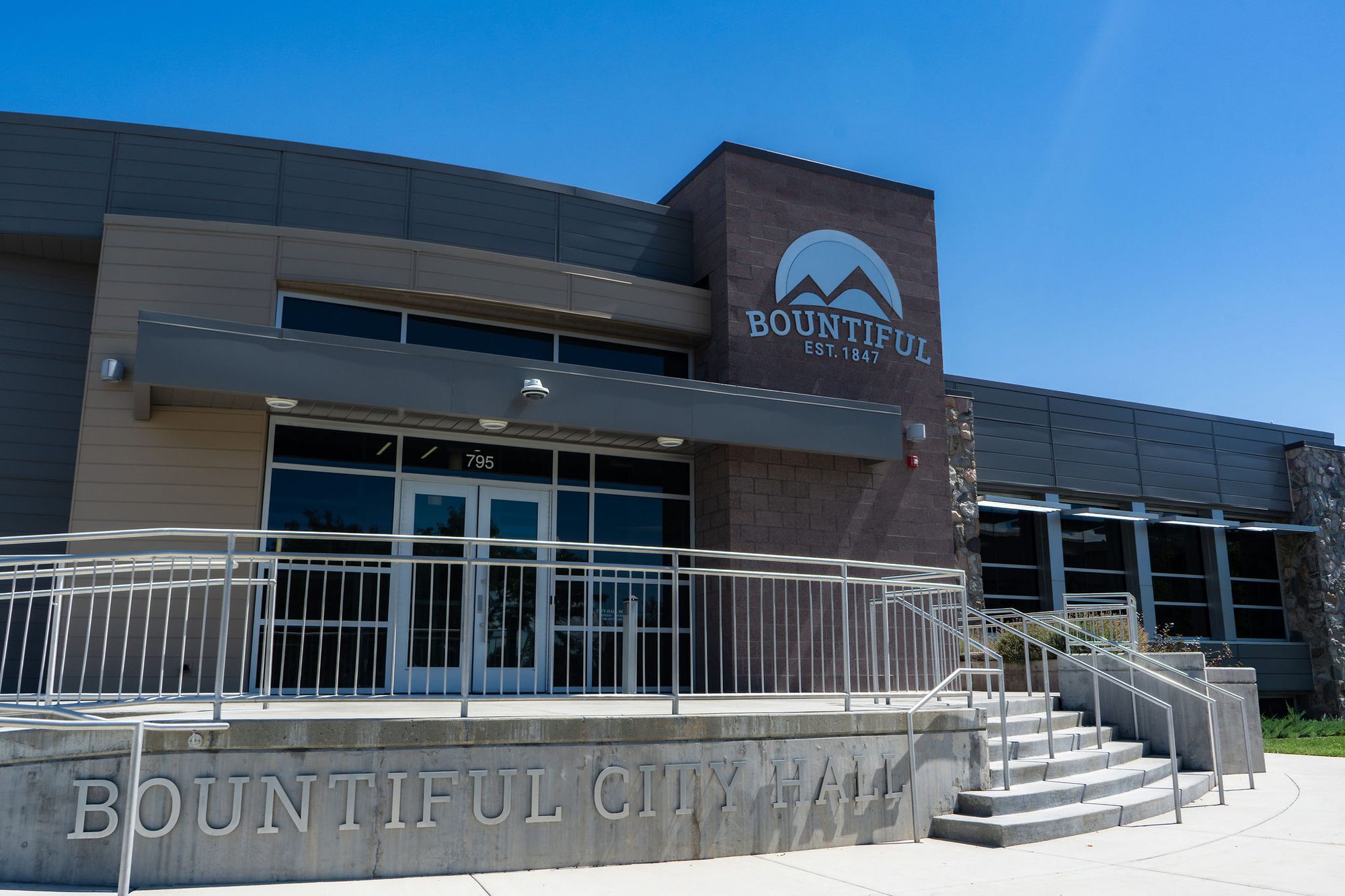 Exterior of a modern two-story city hall building with mountain logo signage.
