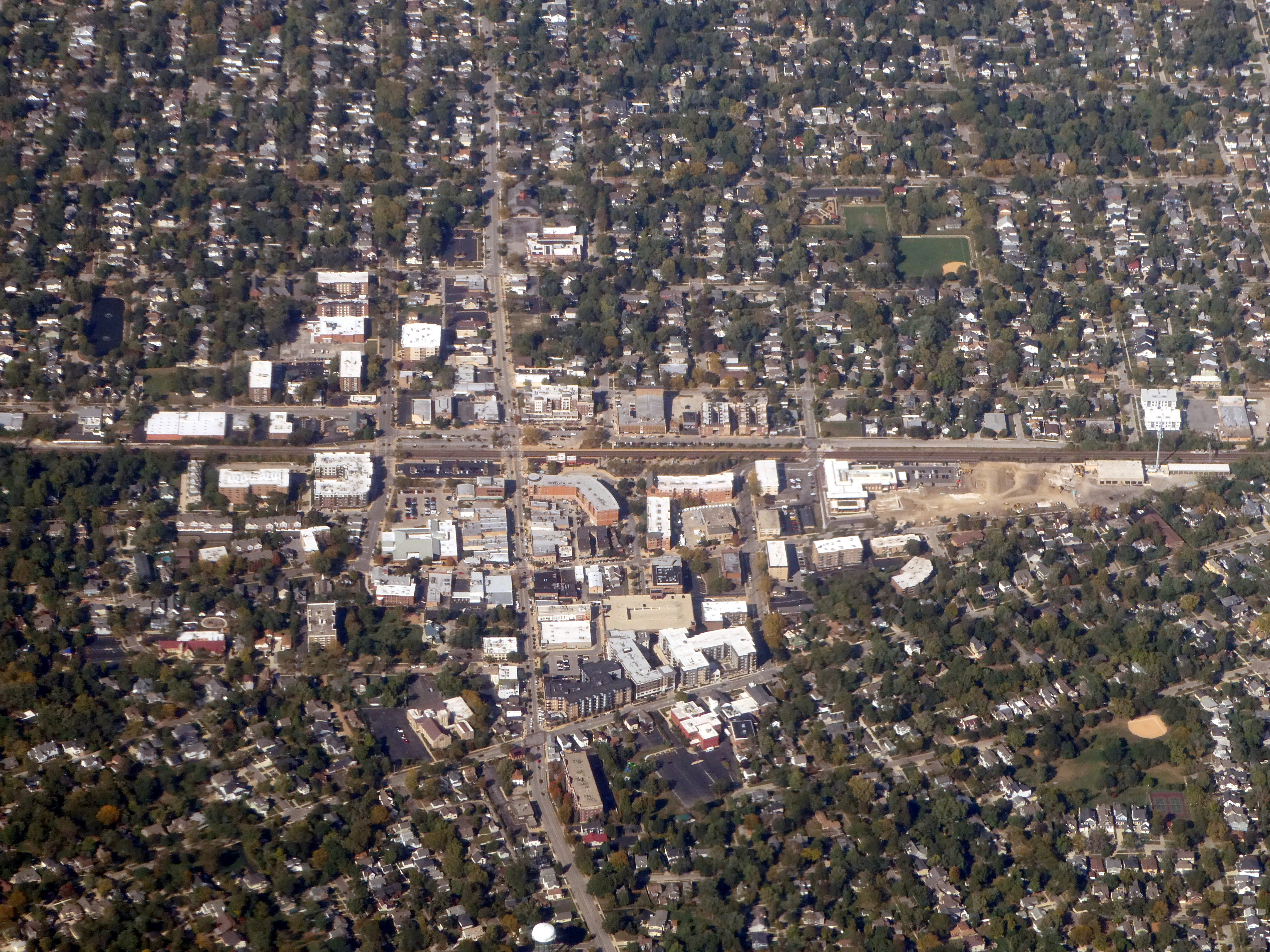 Aerial view of a suburban Illinois city with a downtown commercial district and tree-lined residential streets.