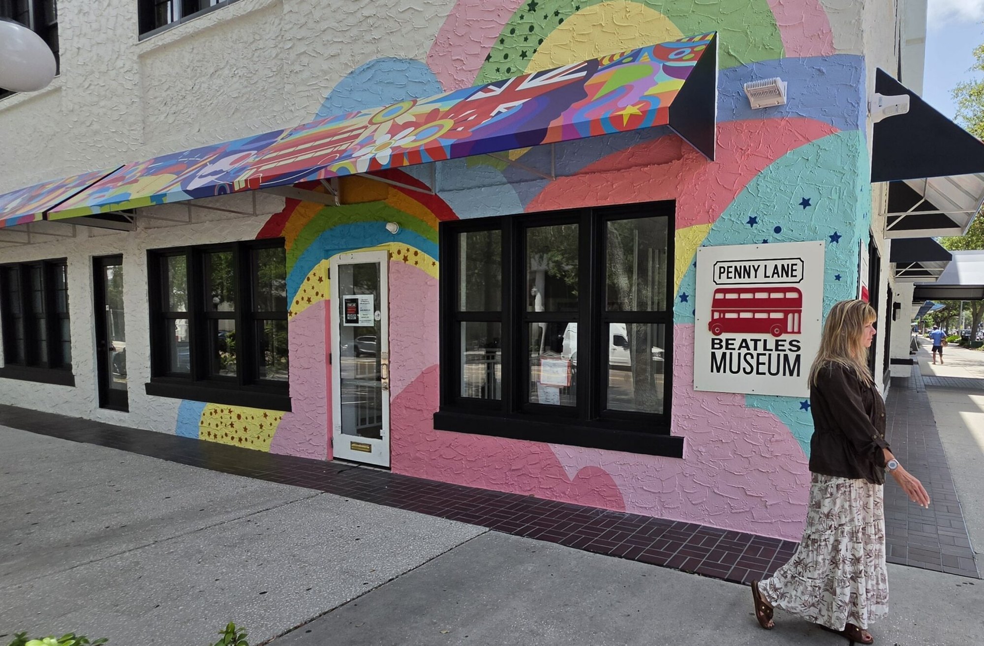 Colorful painted building exterior with a Penny Lane Beatles Museum sign and red double-decker bus graphic.