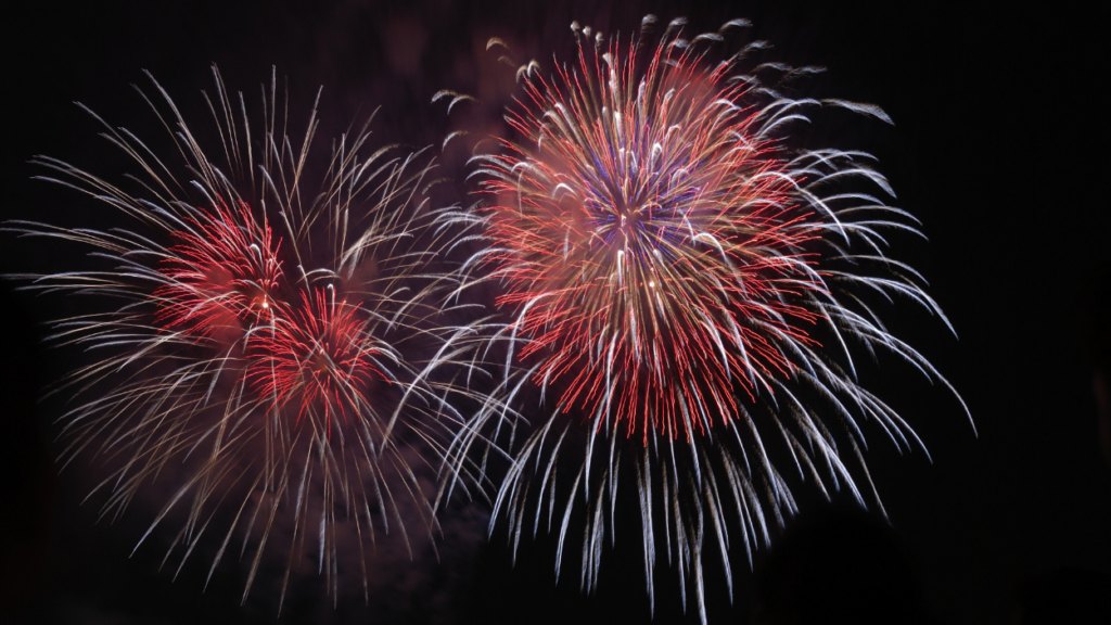 Red, white, and blue fireworks bursting against a dark night sky.