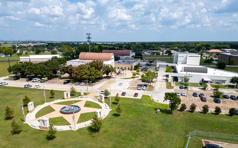 Aerial view of a civic campus with a star-shaped plaza, fountain, flagpoles, and surrounding buildings.