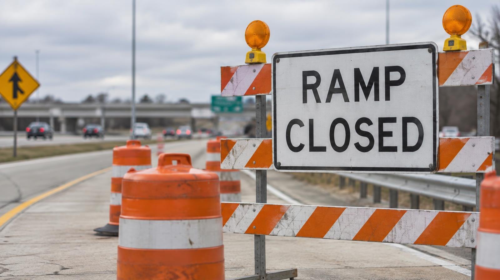Orange construction barrels blocking a highway on-ramp entrance.