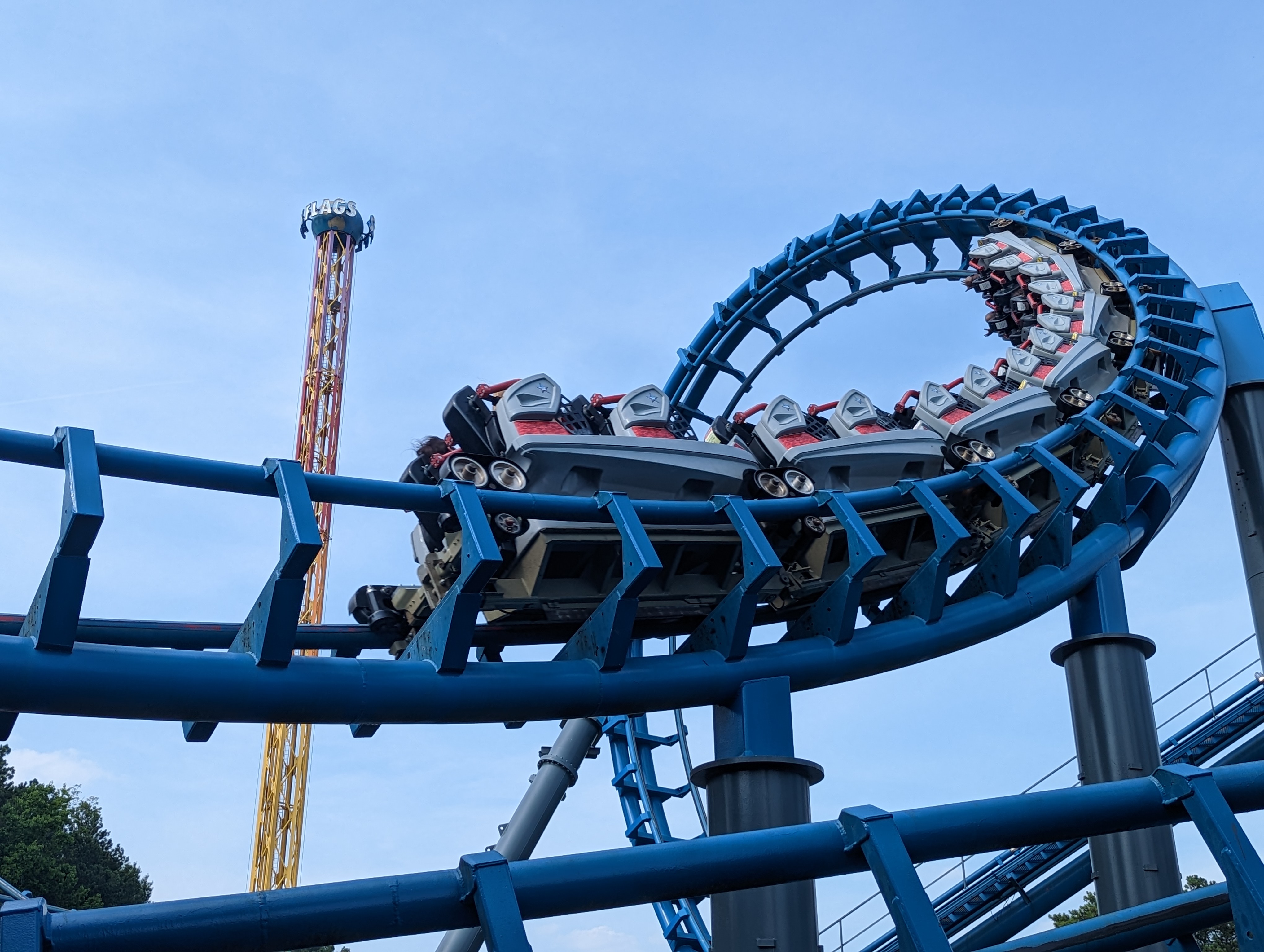 A roller coaster train travels through a full vertical loop on blue steel track.