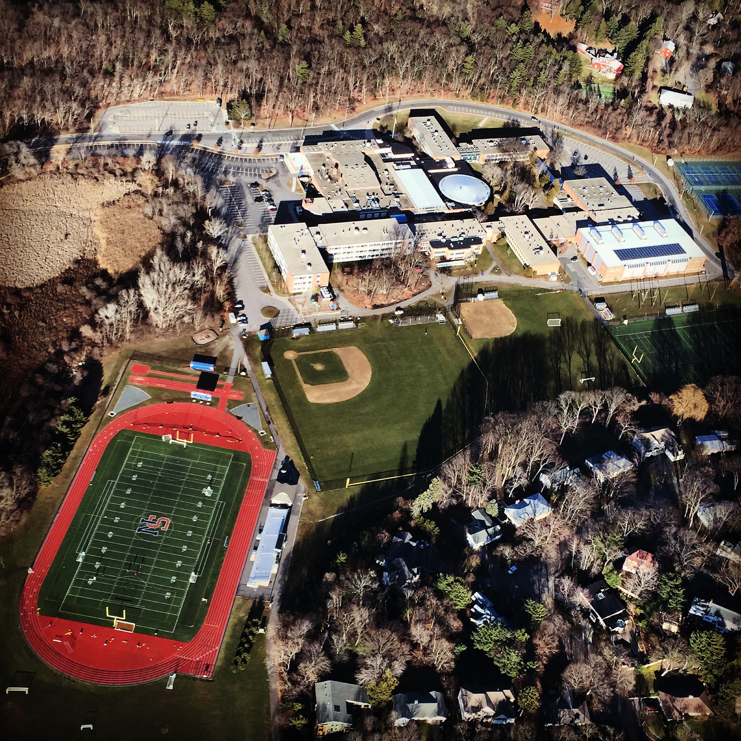 Aerial view of a high school campus with a red running track and athletic fields.