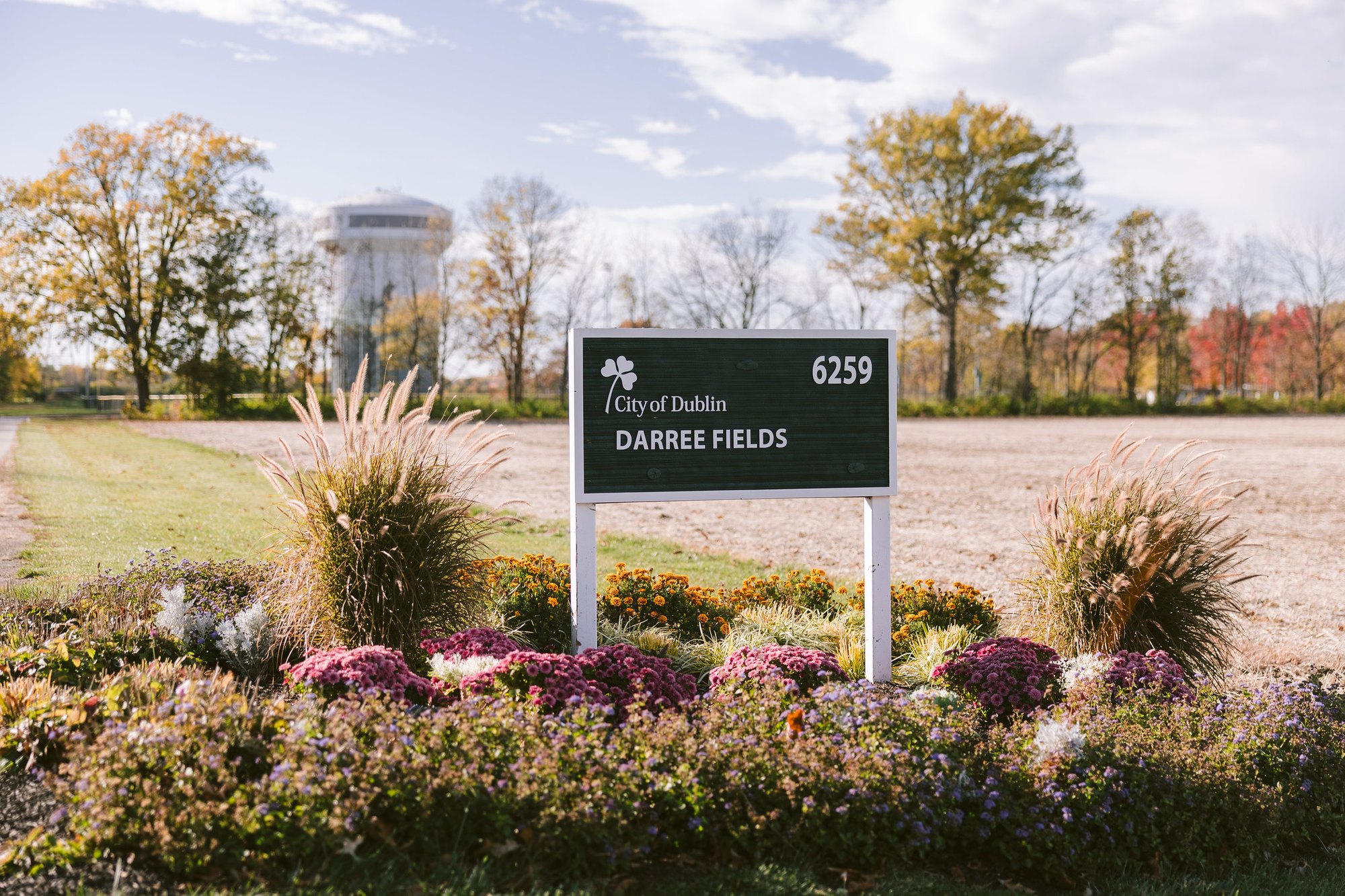 City of Dublin Darree Fields entrance sign with a water tower visible in the background among autumn trees.