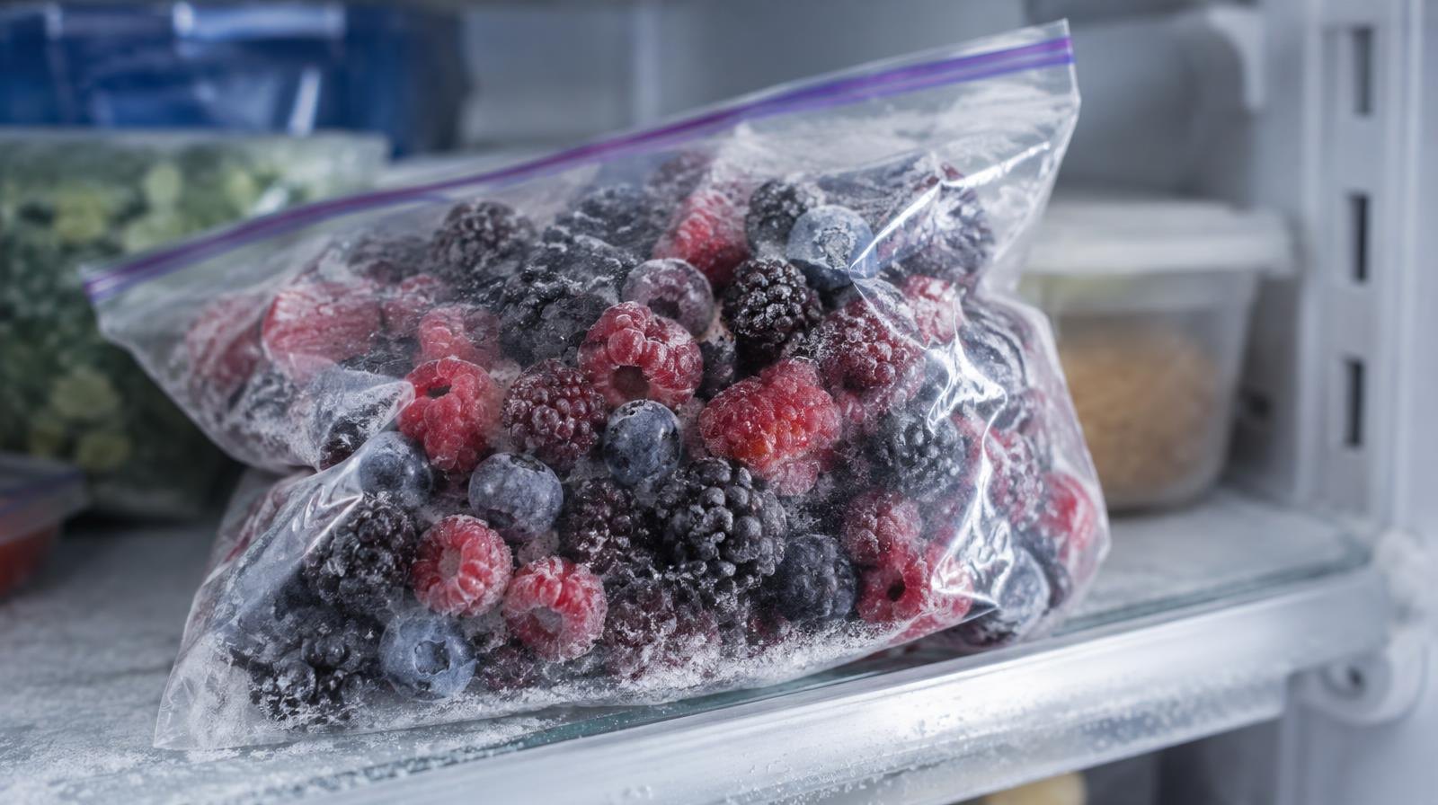 Sealed bag of frozen mixed berries resting on a frosted freezer shelf.