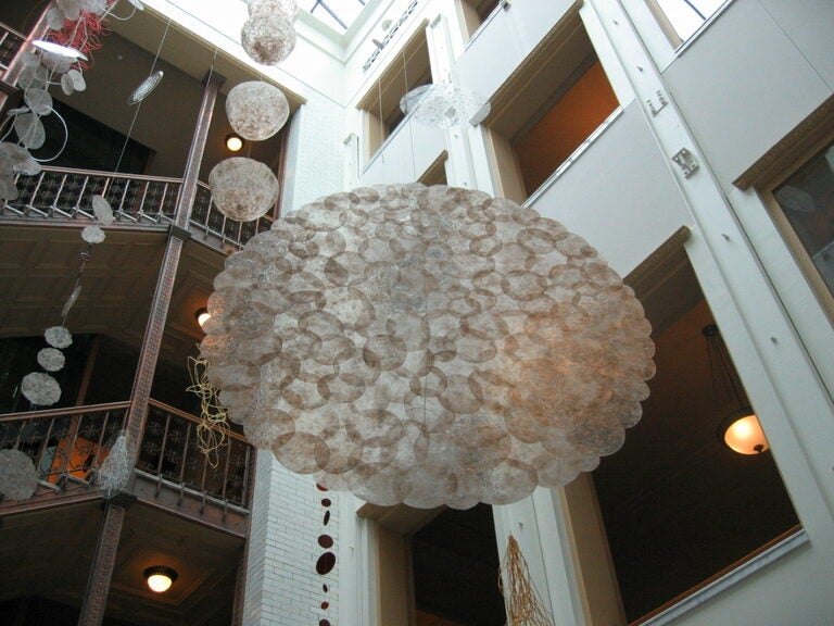 Large translucent spherical sculpture hanging in a multi-story building atrium.