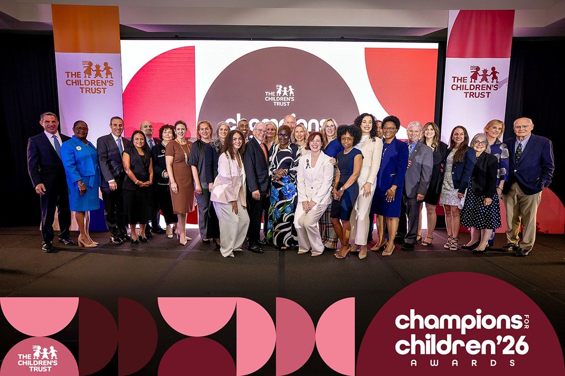 Large group of adults posed on a stage in front of a Children's Trust Champions for Children Awards backdrop.