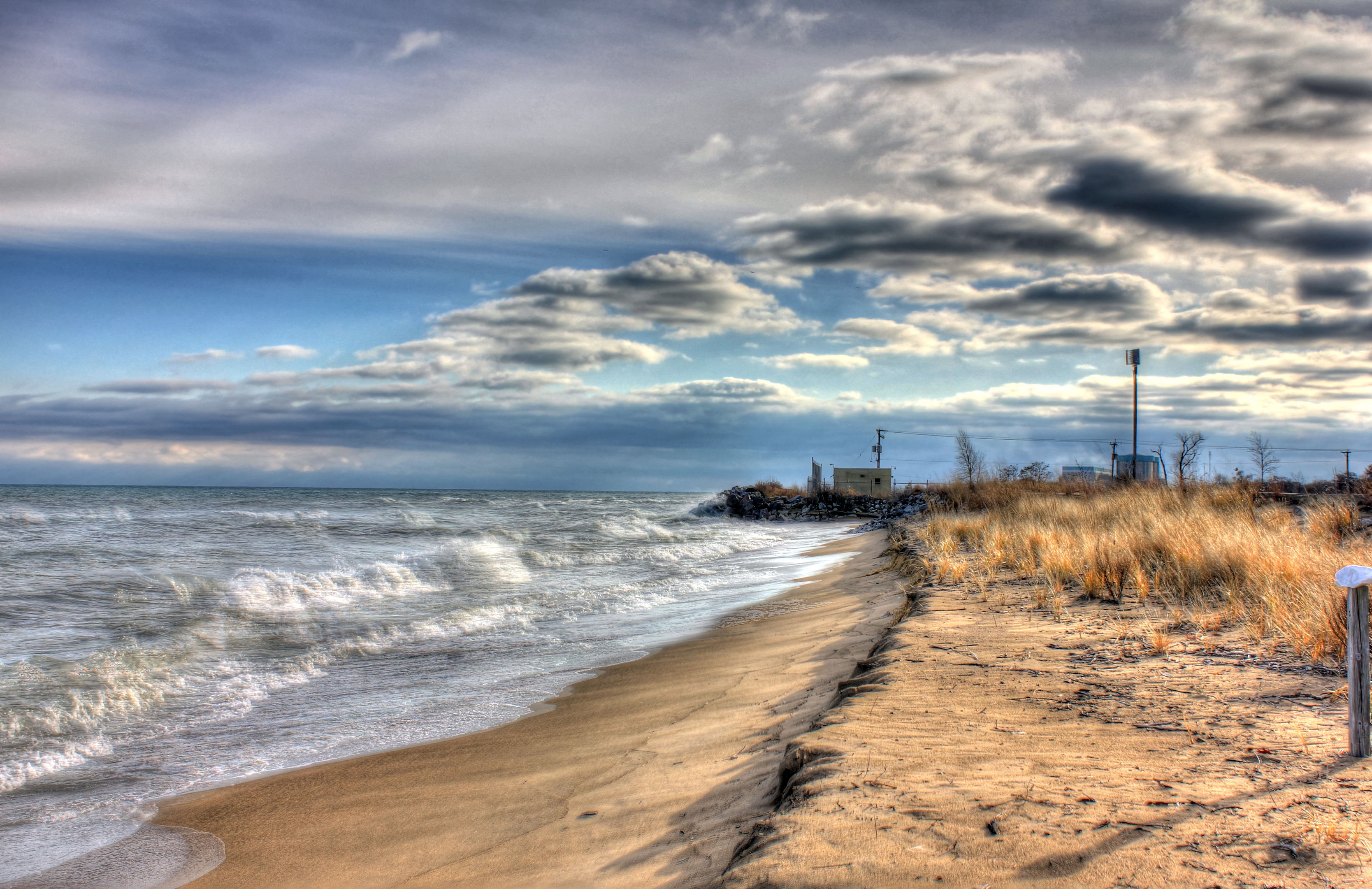 Sandy Lake Michigan shoreline with waves breaking under a dramatic overcast sky.