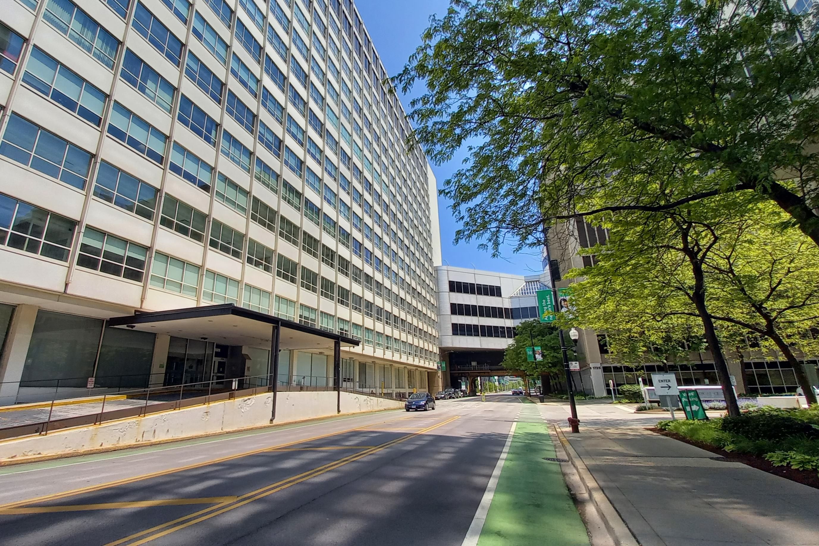Large multi-story medical center building lining an urban street with a green bike lane.
