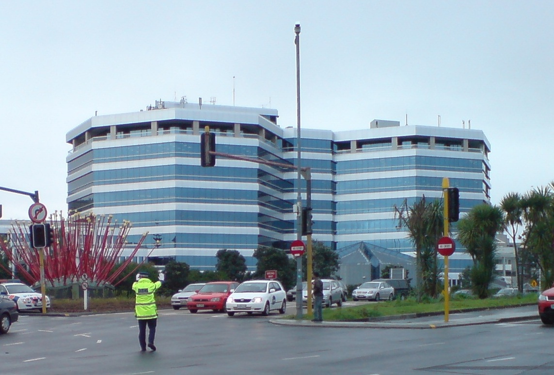 Uniformed officer in yellow vest directing traffic by hand at a busy intersection.