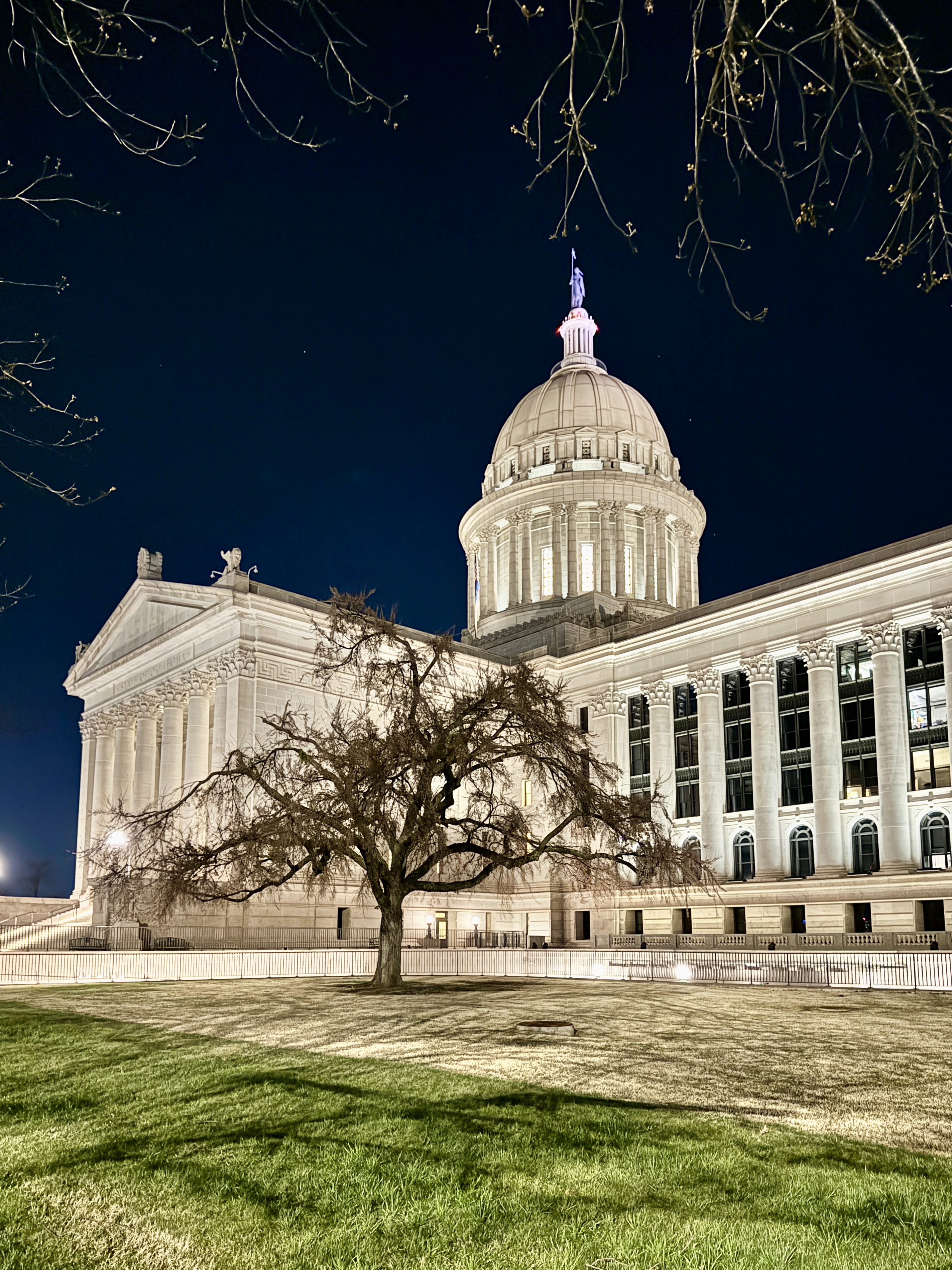 Oklahoma State Capitol building illuminated at night with dome and columns visible.