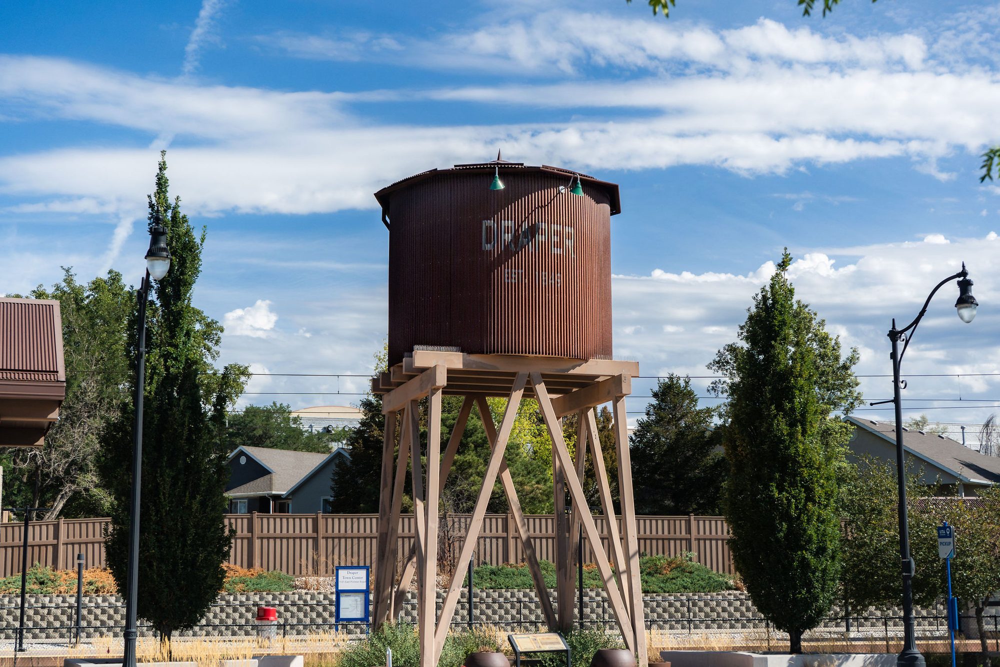 Weathered wooden water tower on a timber frame surrounded by cypress trees.
