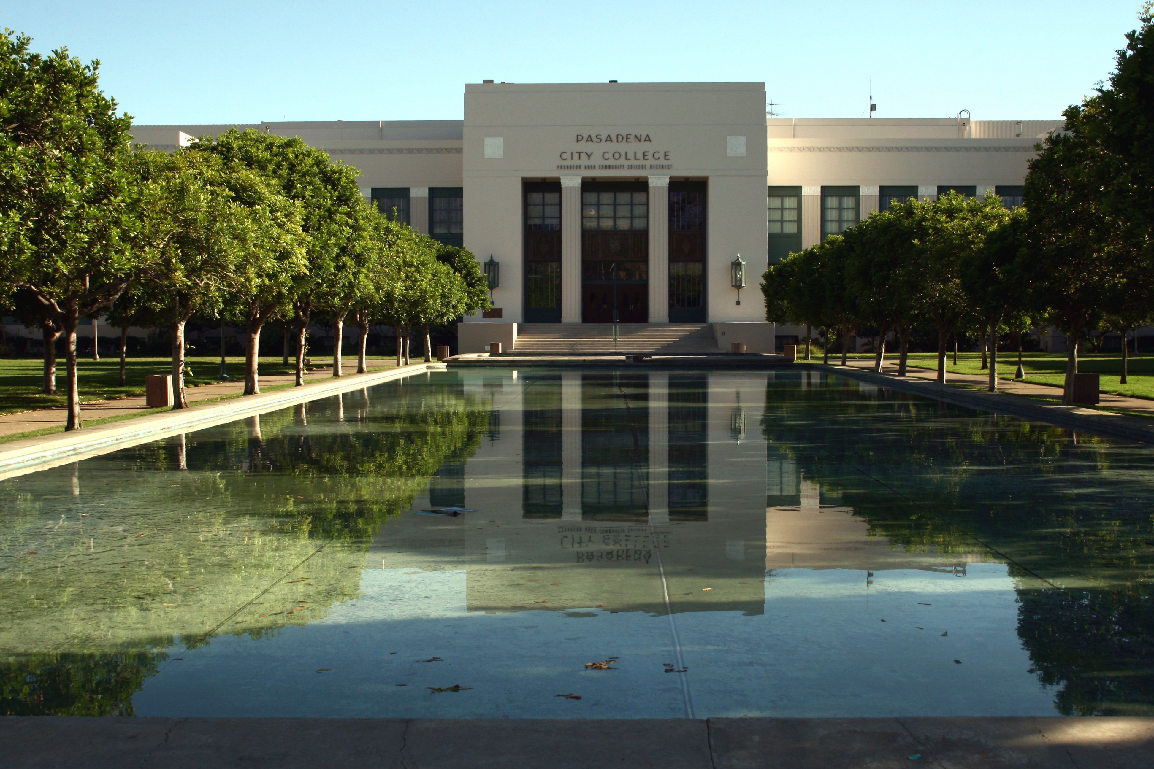 Pasadena City College main building with a reflecting pool and tree-lined walkway on a sunny day.