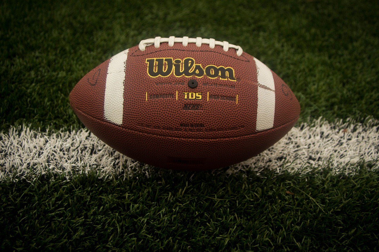 Football resting on the turf of a high school football field.