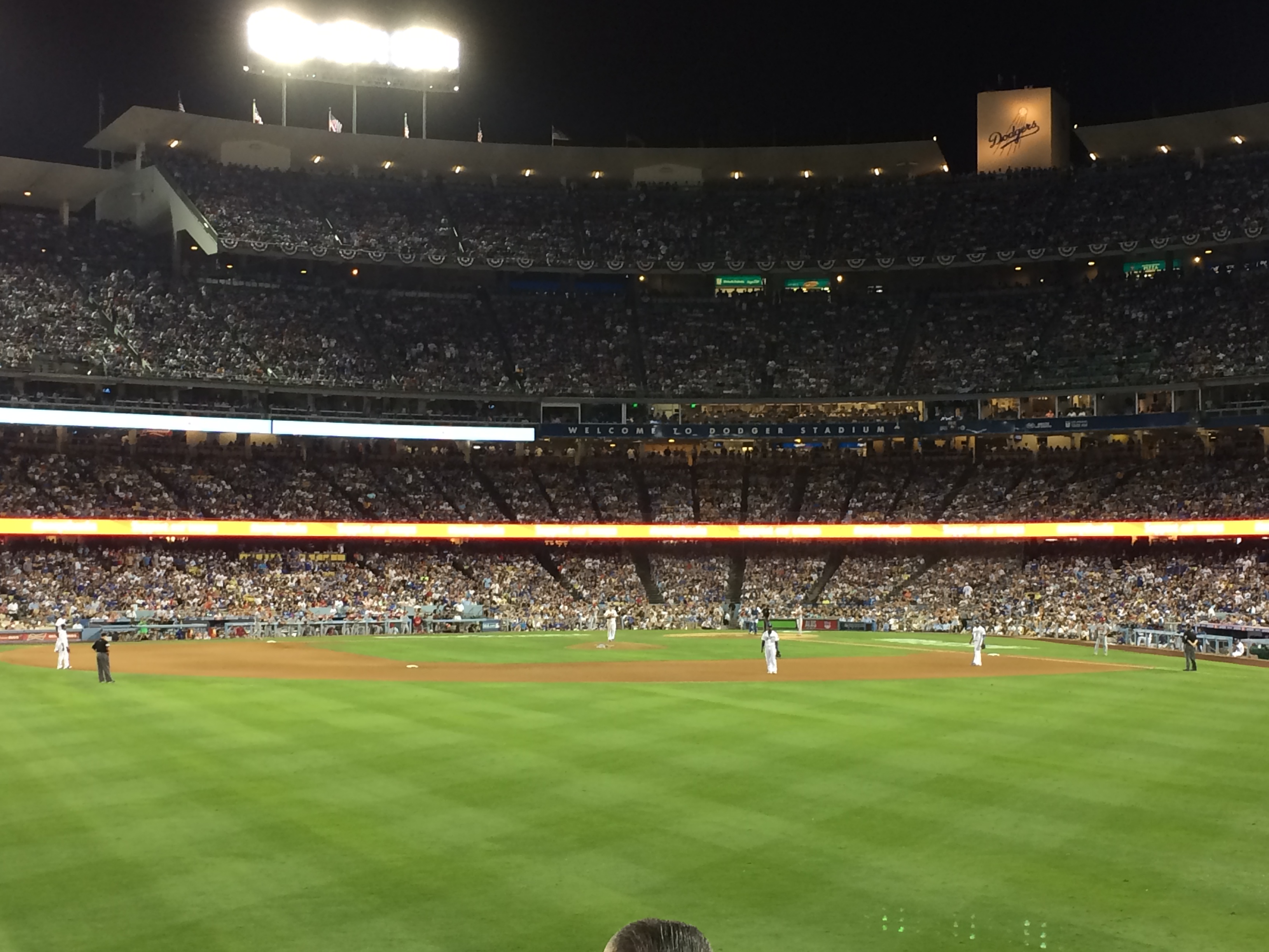 Night baseball game at Dodger Stadium viewed from center field with a packed crowd under stadium lights.