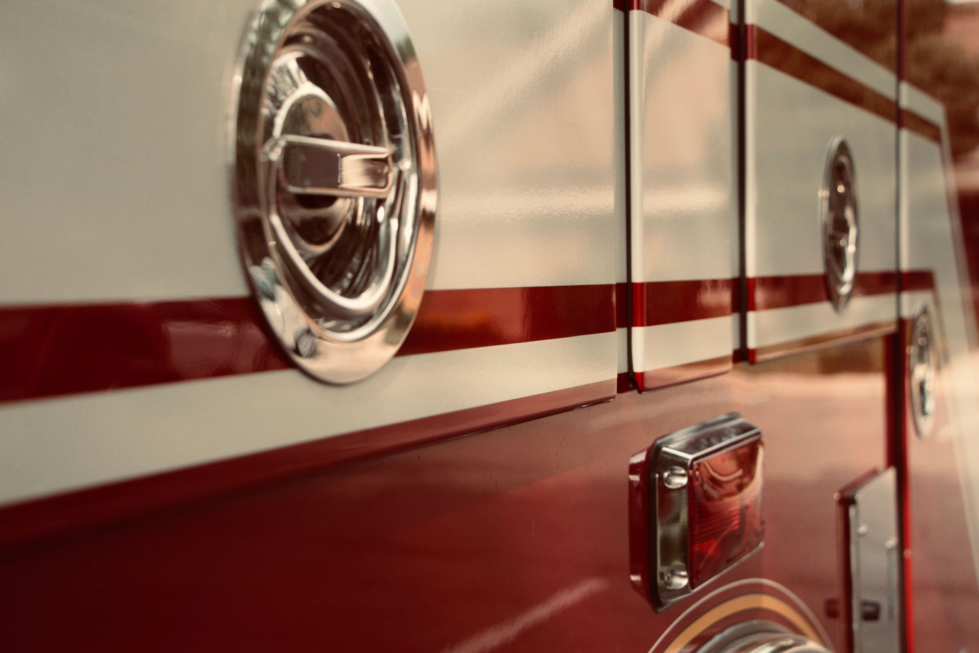 Close-up of a vintage fire truck showing chrome handles and red and white stripes.