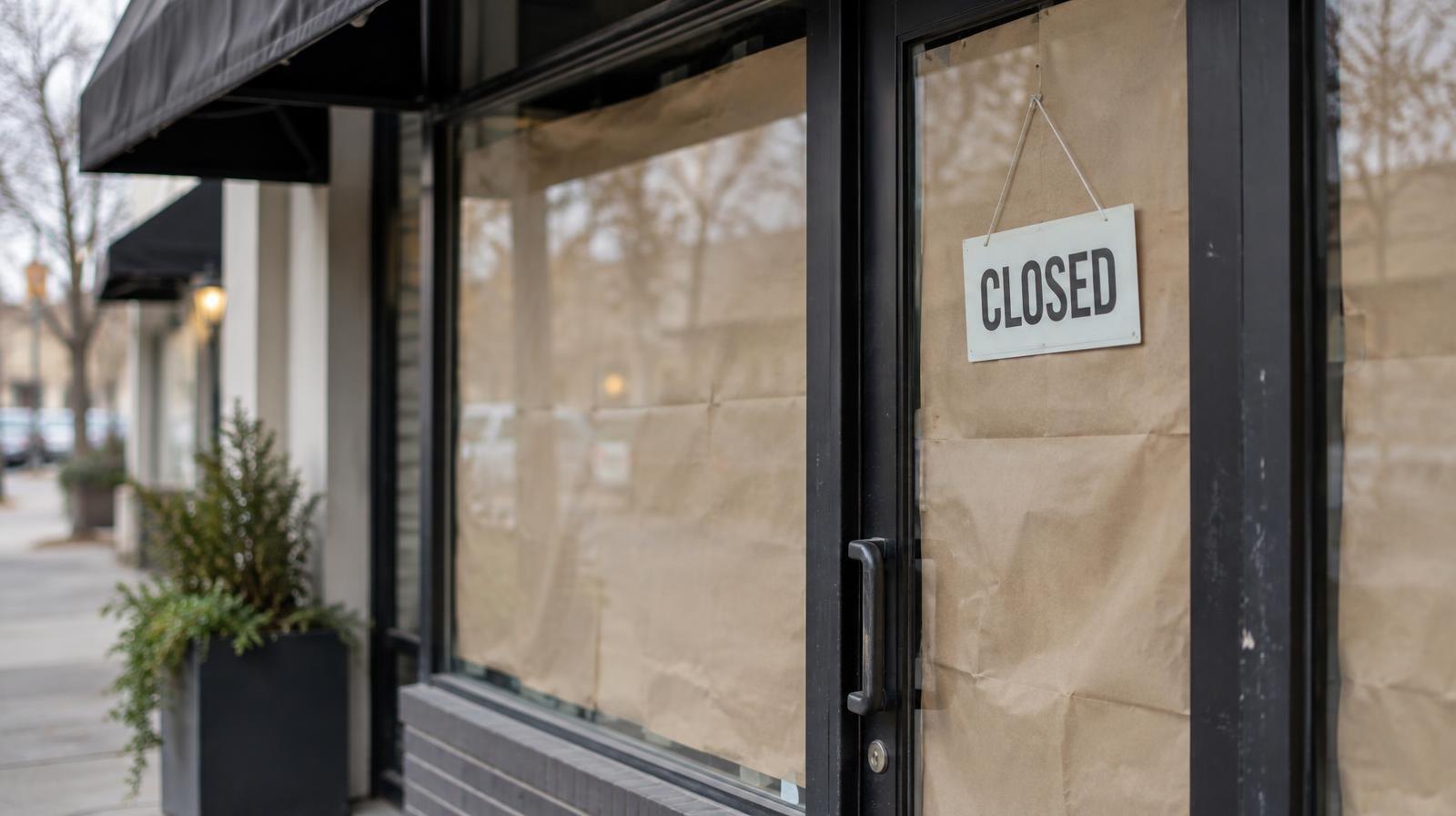 Paper-covered glass storefront door and window of a closed shop with a dark awning.