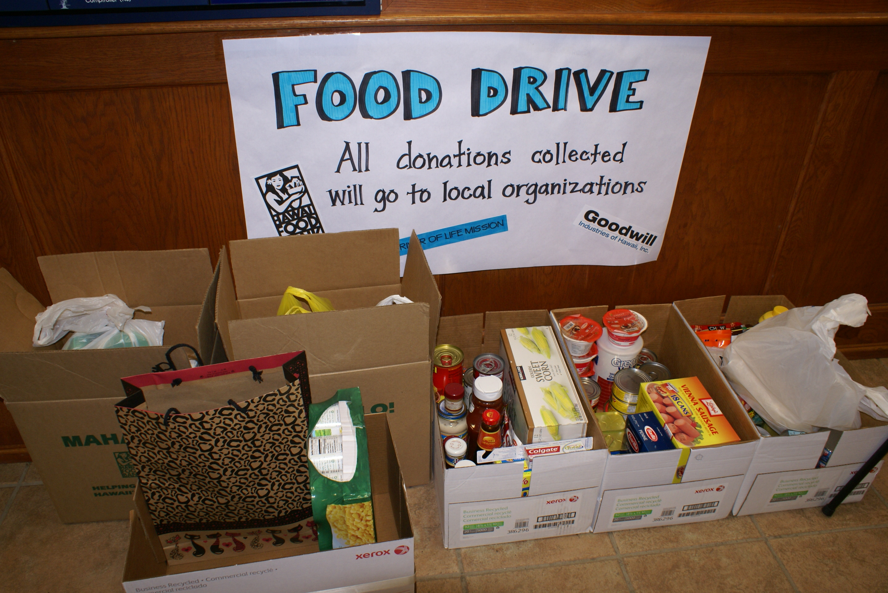 Cardboard boxes filled with canned goods and non-perishable food items on a floor.