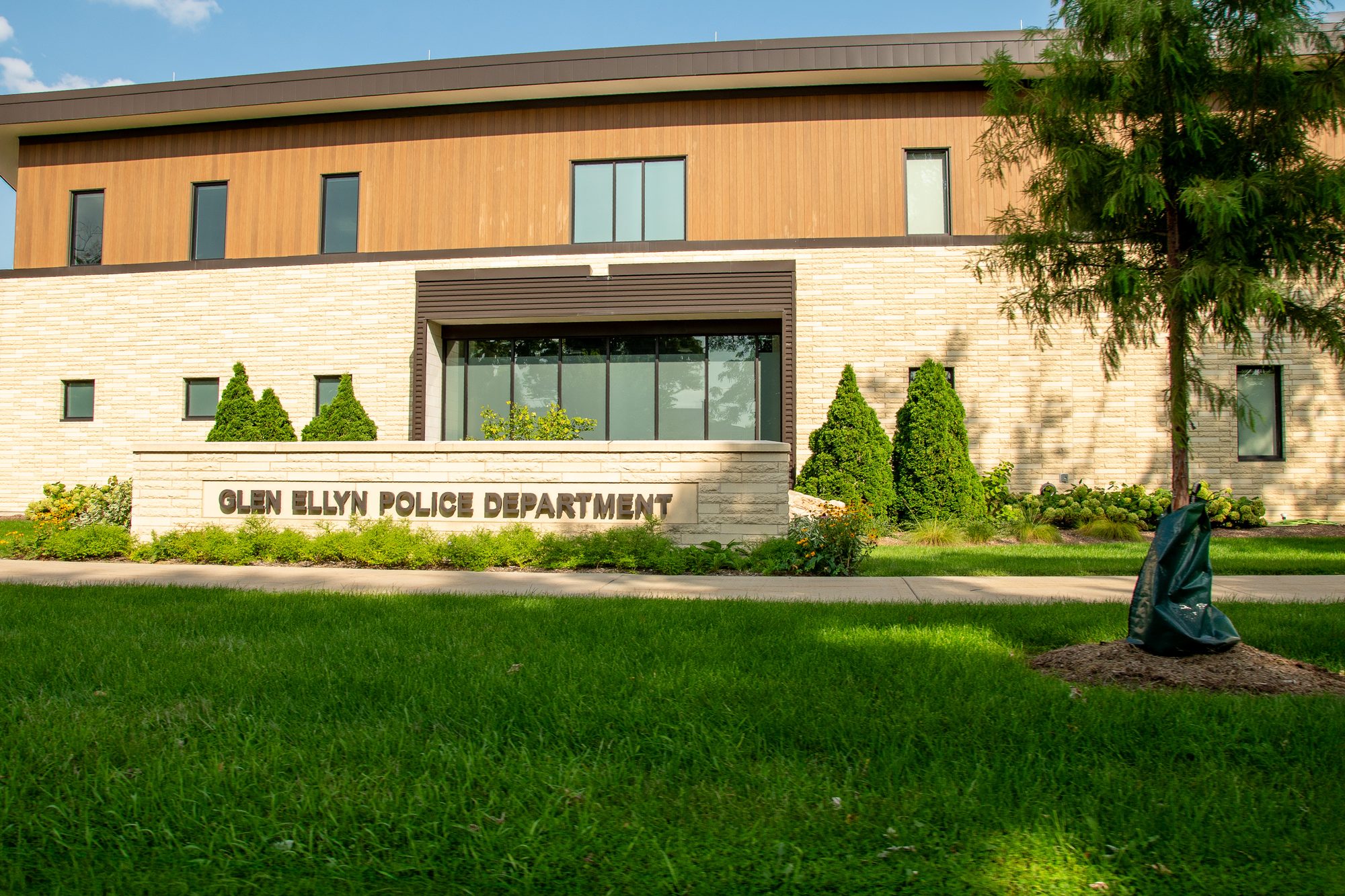 Exterior of a modern two-story police department building with stone and wood-panel facade.