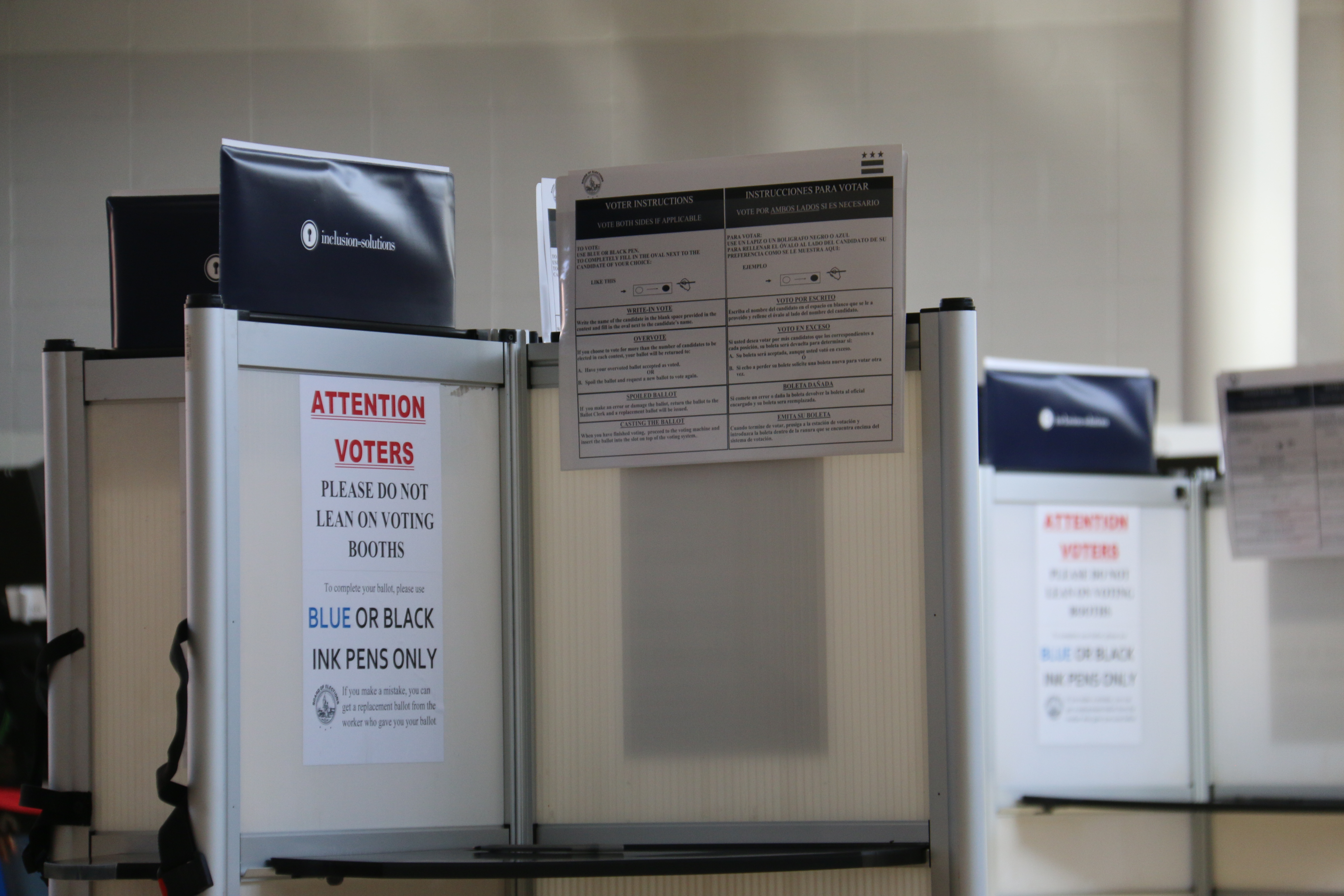 A row of voting booths with privacy dividers and voter instruction signs.