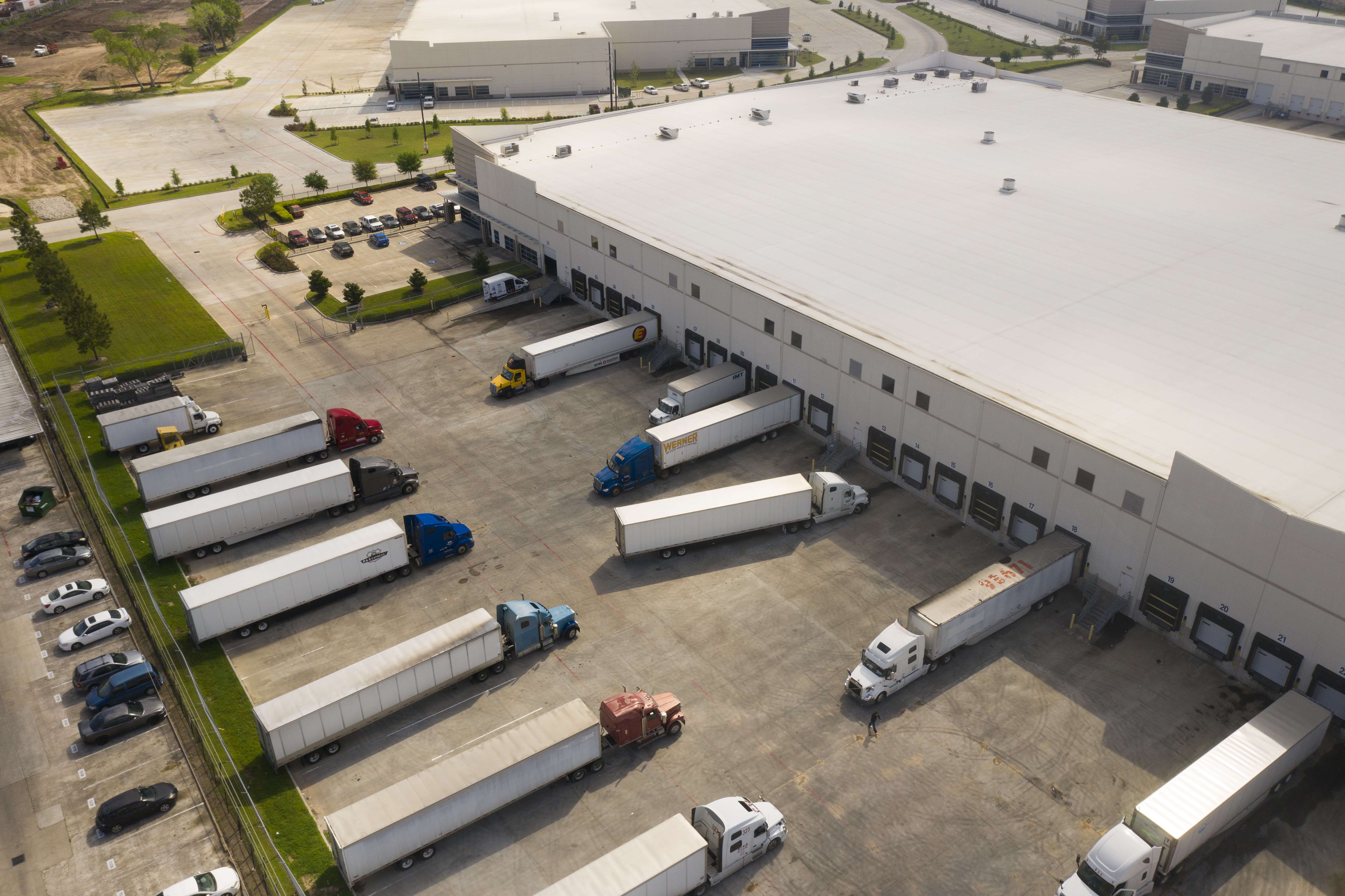 Aerial view of a large warehouse distribution center with loading docks and semi-trucks.