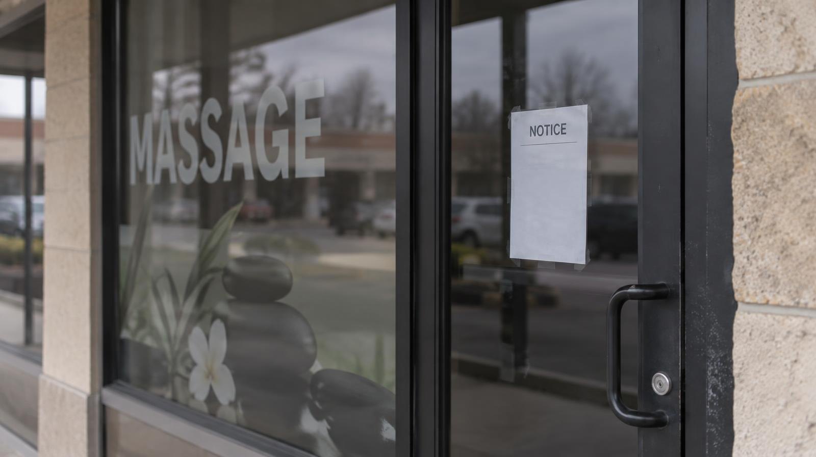 Darkened storefront with a paper notice posted on a glass door.