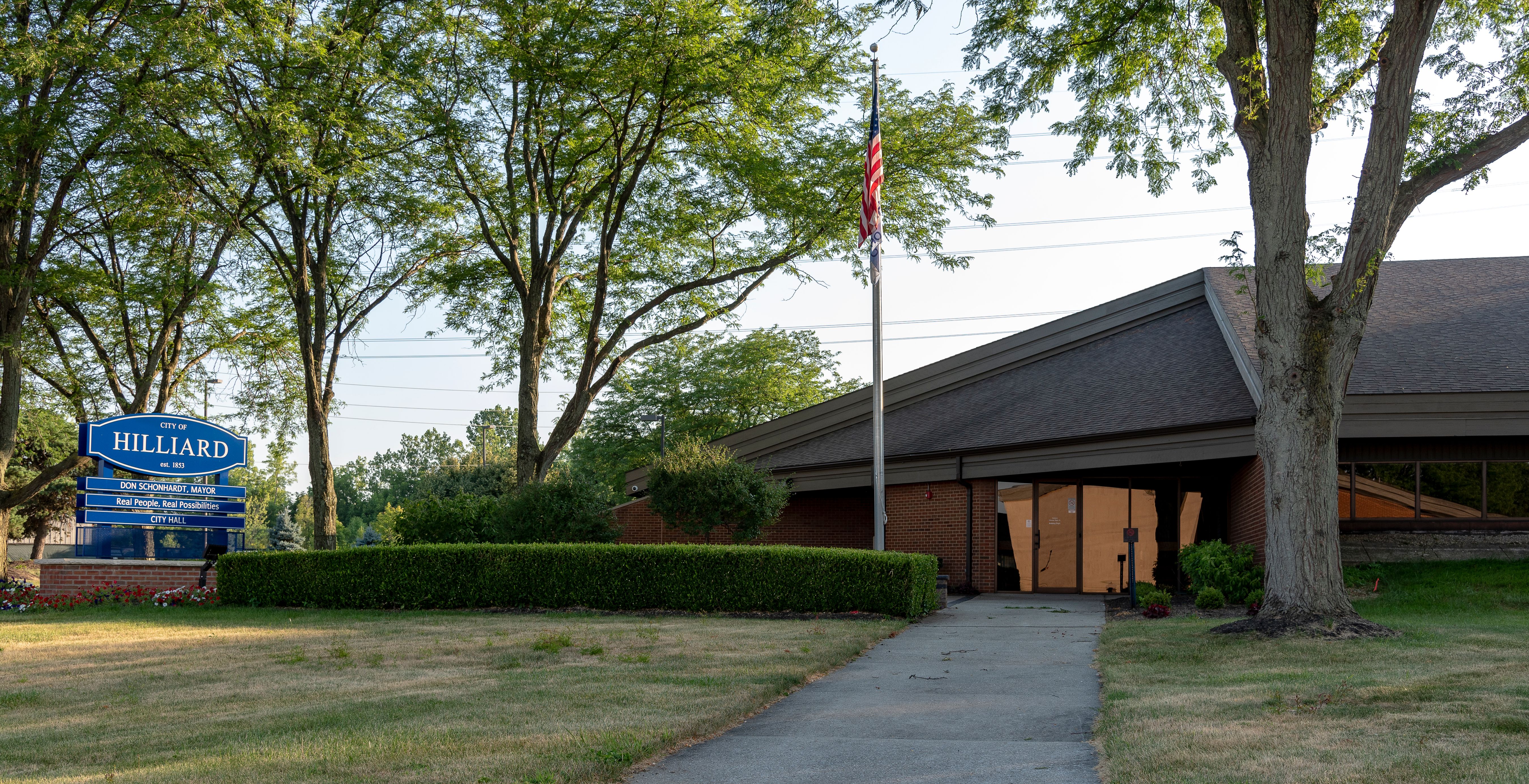 Exterior of a low-profile municipal building with a 'Hilliard' sign and American flag.