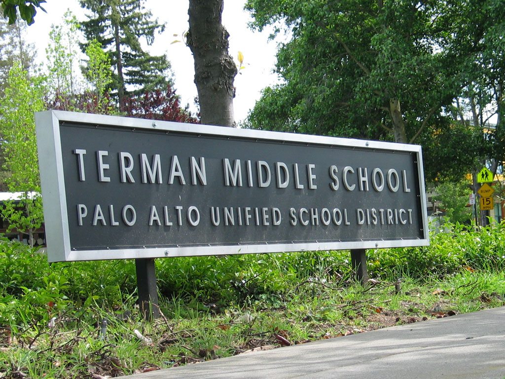 Outdoor sign reading Terman Middle School Palo Alto Unified School District on two posts amid trees