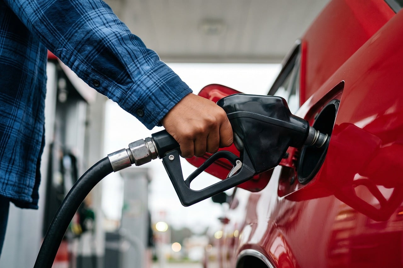 Close-up of a gas pump nozzle with a fuel dispenser in the background.