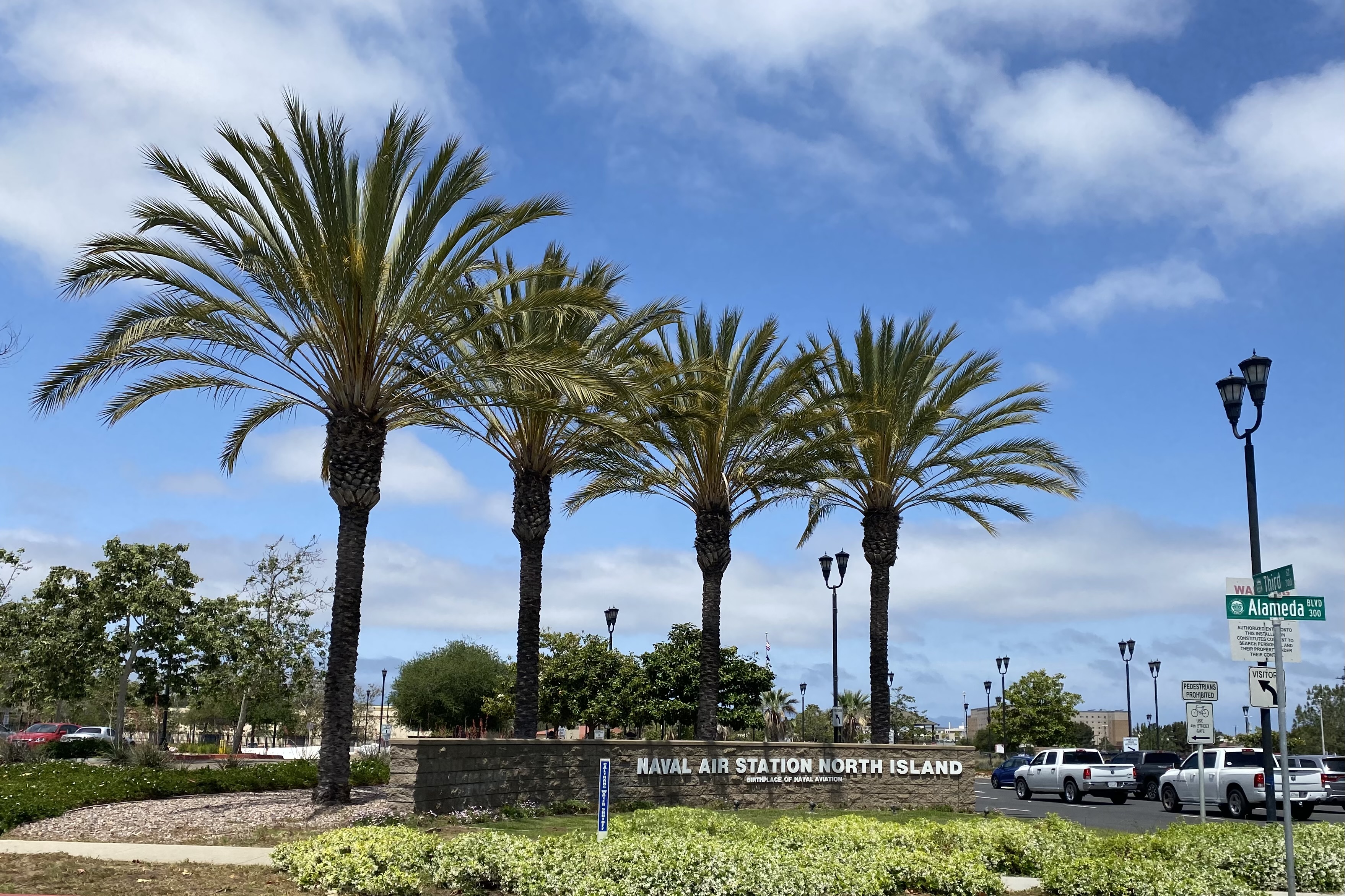 Entrance sign for Naval Air Station North Island flanked by tall palm trees.