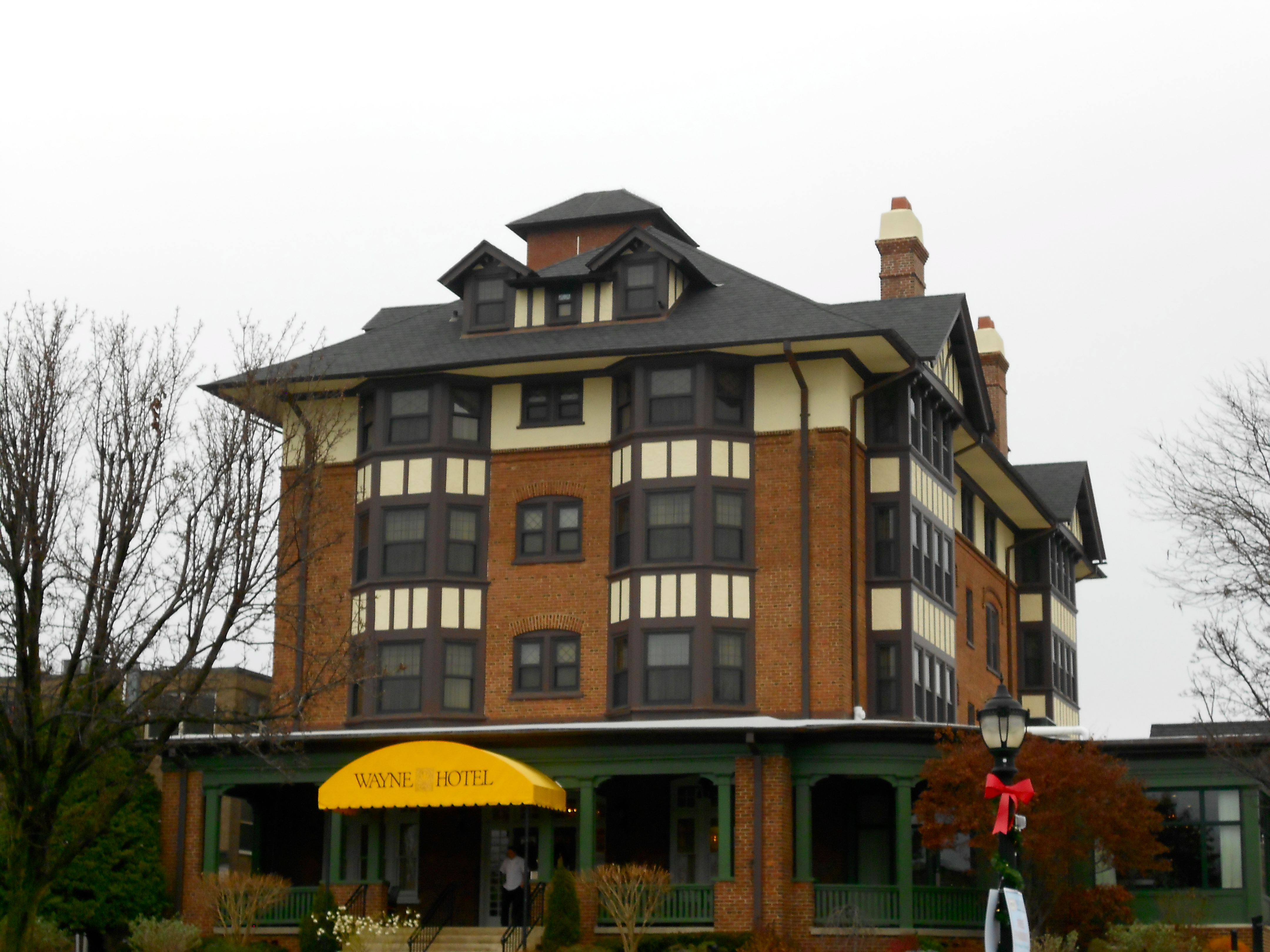 Tudor-style brick Wayne Hotel building with yellow awning on East Lancaster Avenue.