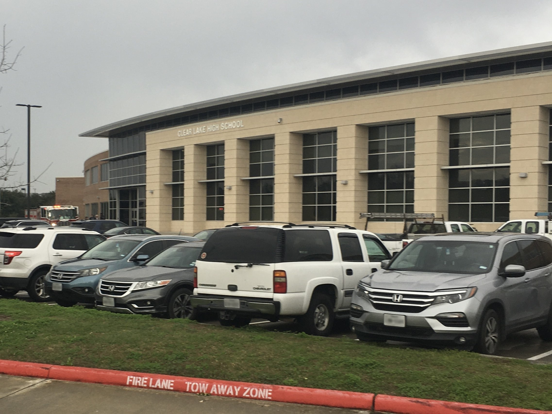 Exterior of a high school building with a large parking lot on a cloudy day.