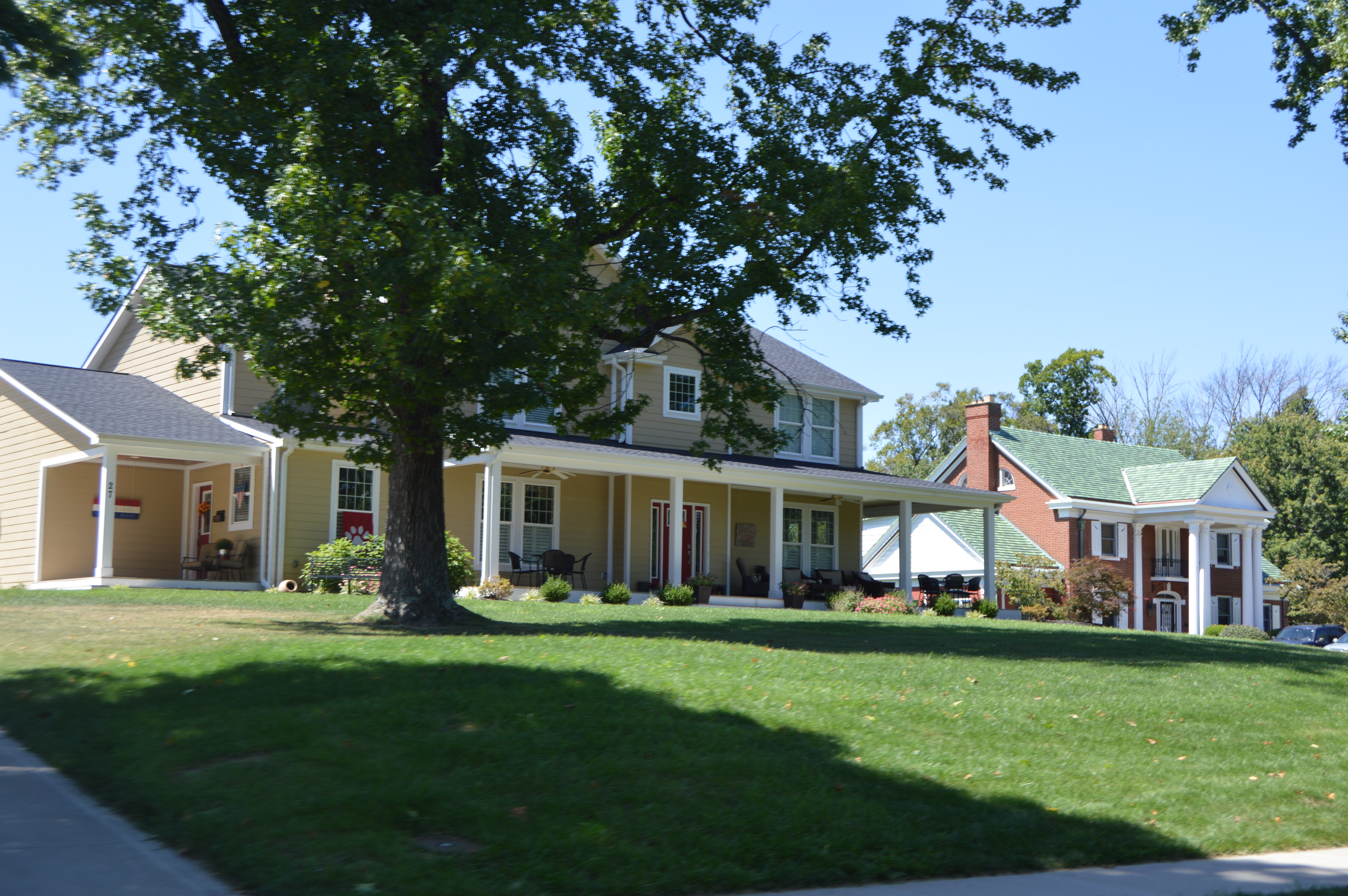 Two-story colonial-style homes with covered porches along a tree-lined residential street.