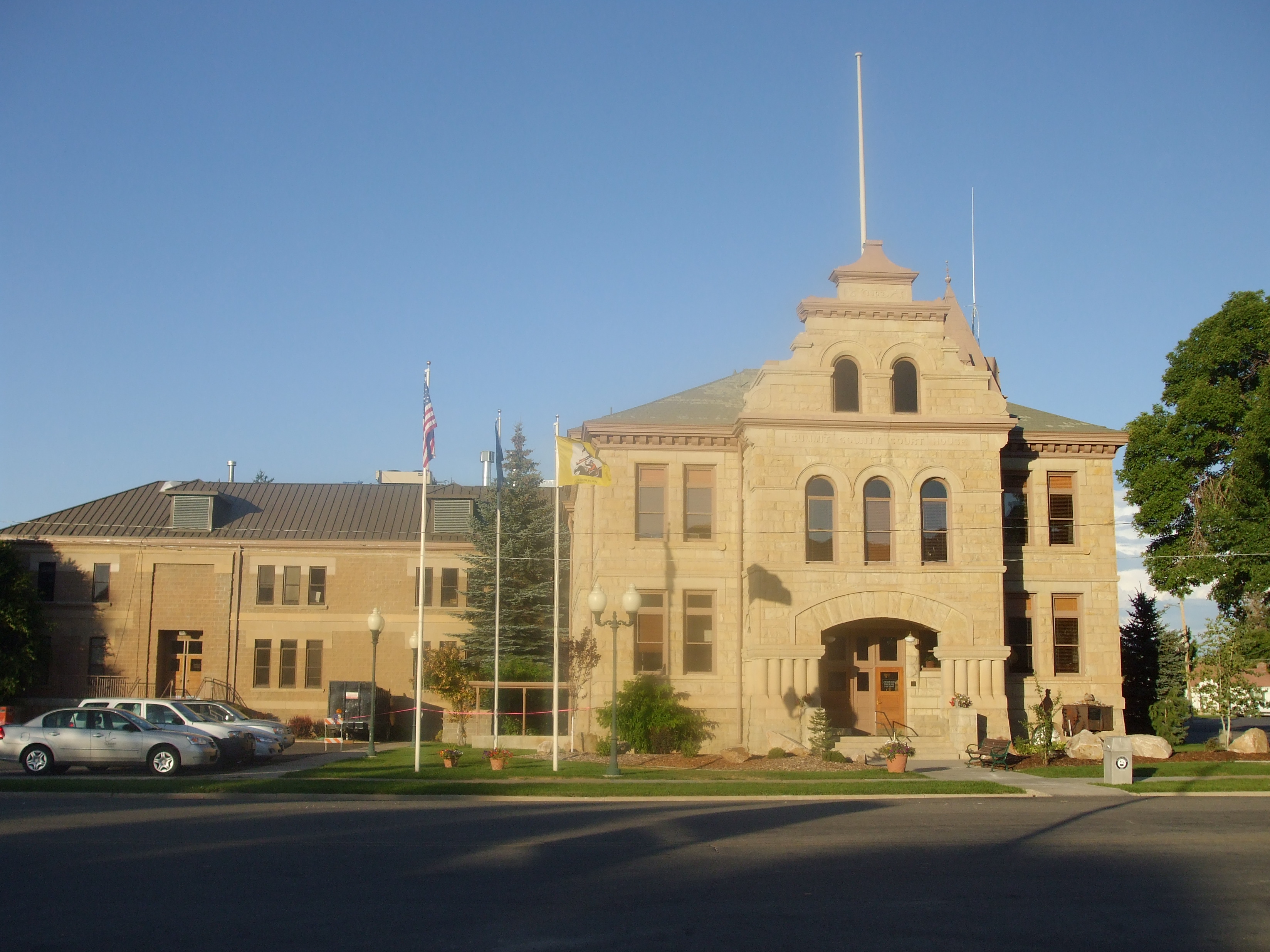 Historic sandstone courthouse with a central tower, arched entry, and American flag on a flagpole.