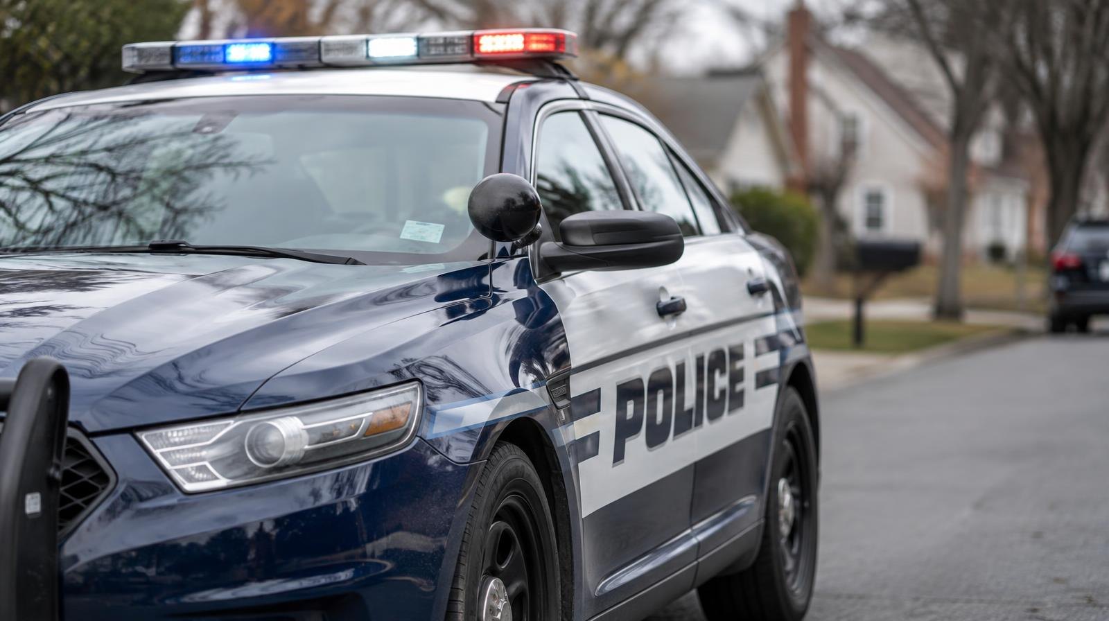 A navy blue and white police patrol car parked on a suburban street.
