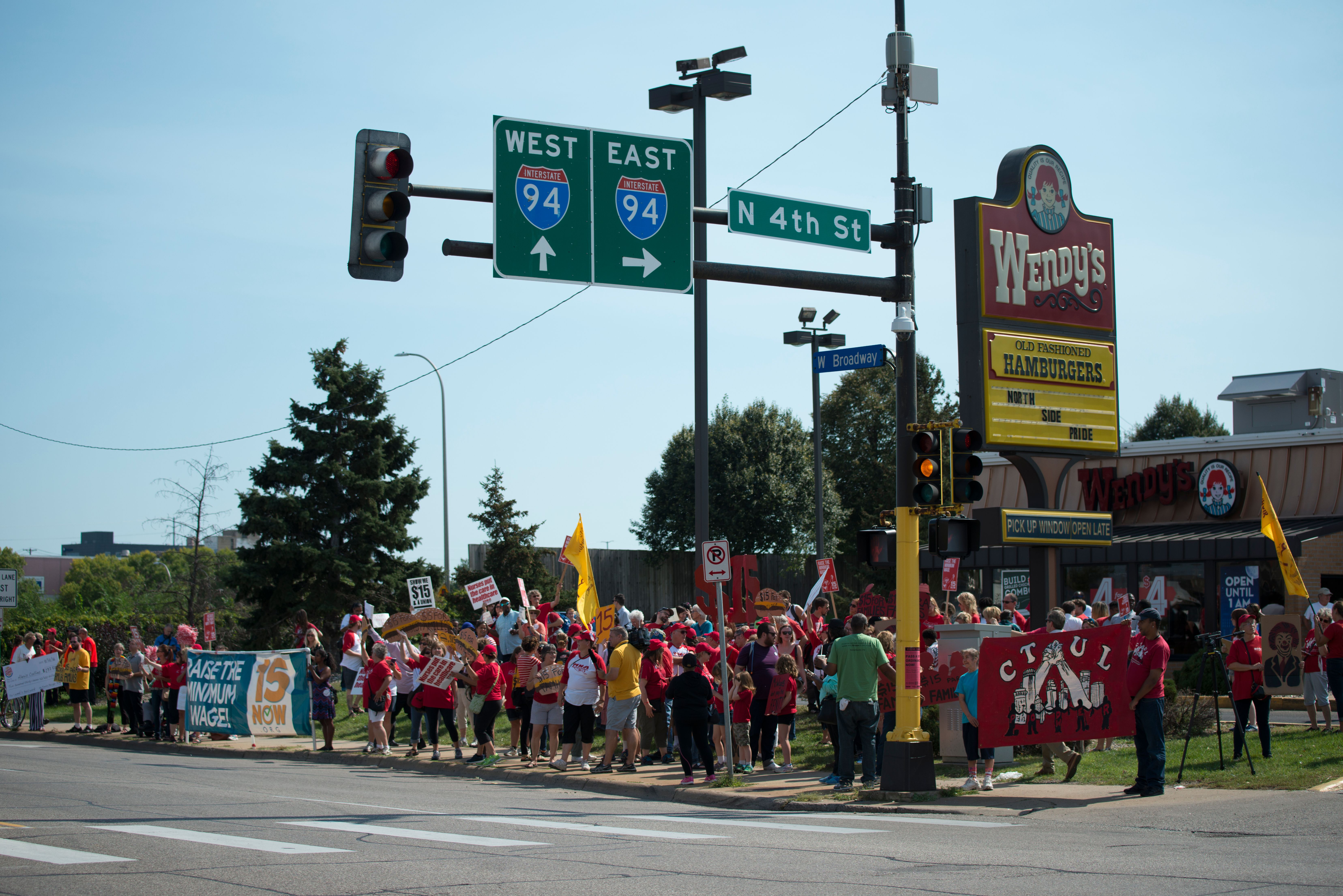 Crowd of protesters holding signs outside a fast-food restaurant calling for a fifteen-dollar minimum wage.