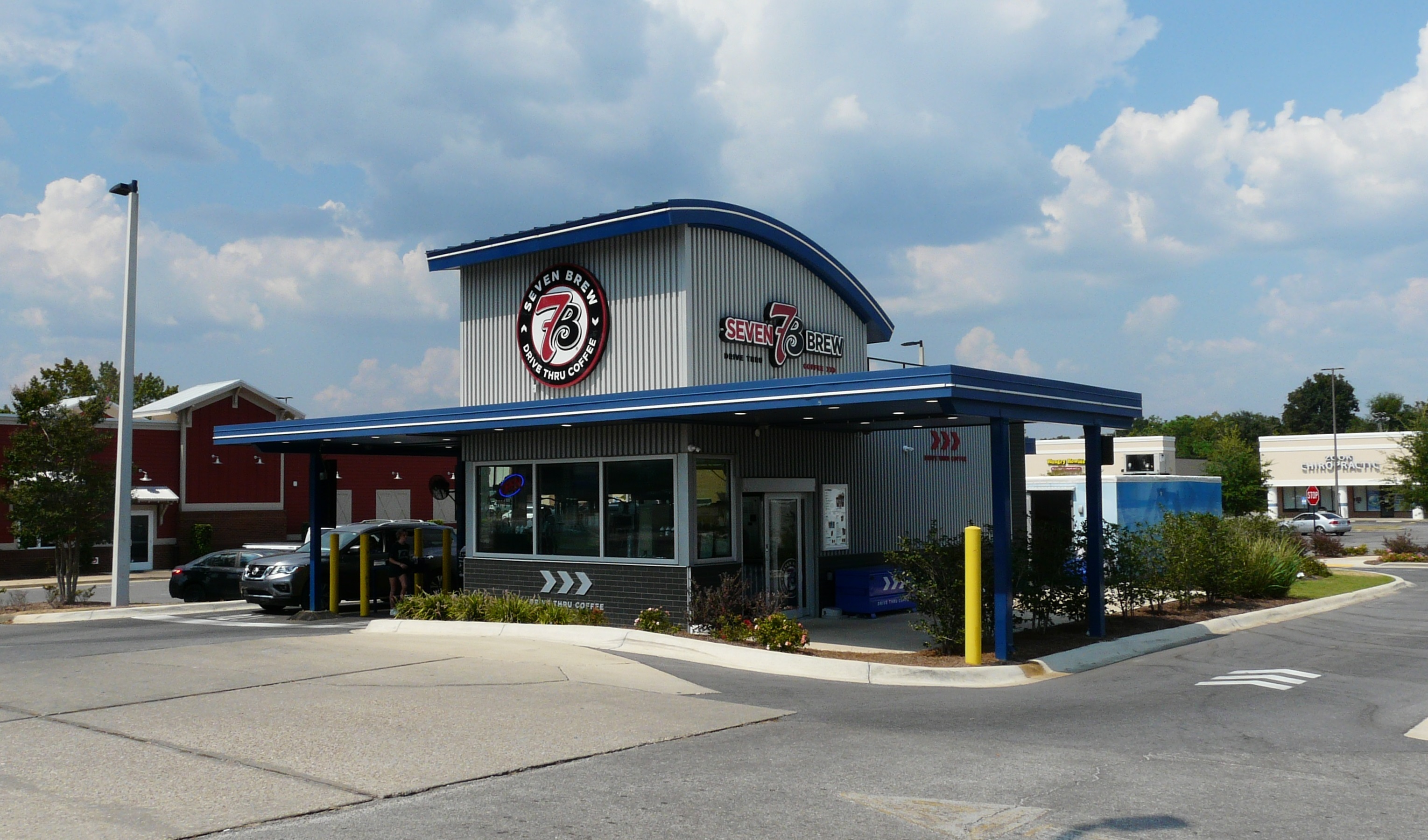 A 7 Brew Coffee drive-thru stand with blue and gray exterior and two drive-thru lanes.