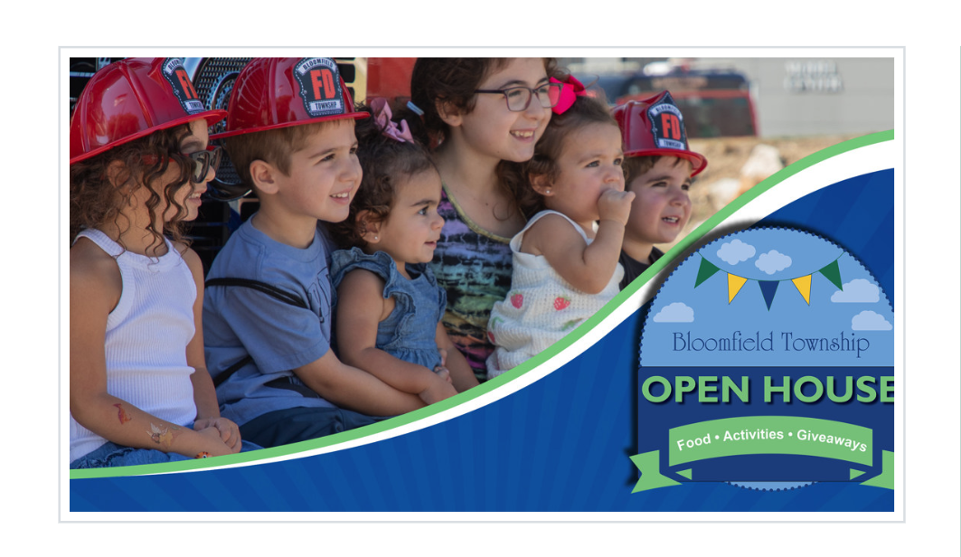 Children in red firefighter helmets sit together at a Bloomfield Township event, next to graphic text reading "Bloomfield Township Open House, Food, Activities, Giveaways."