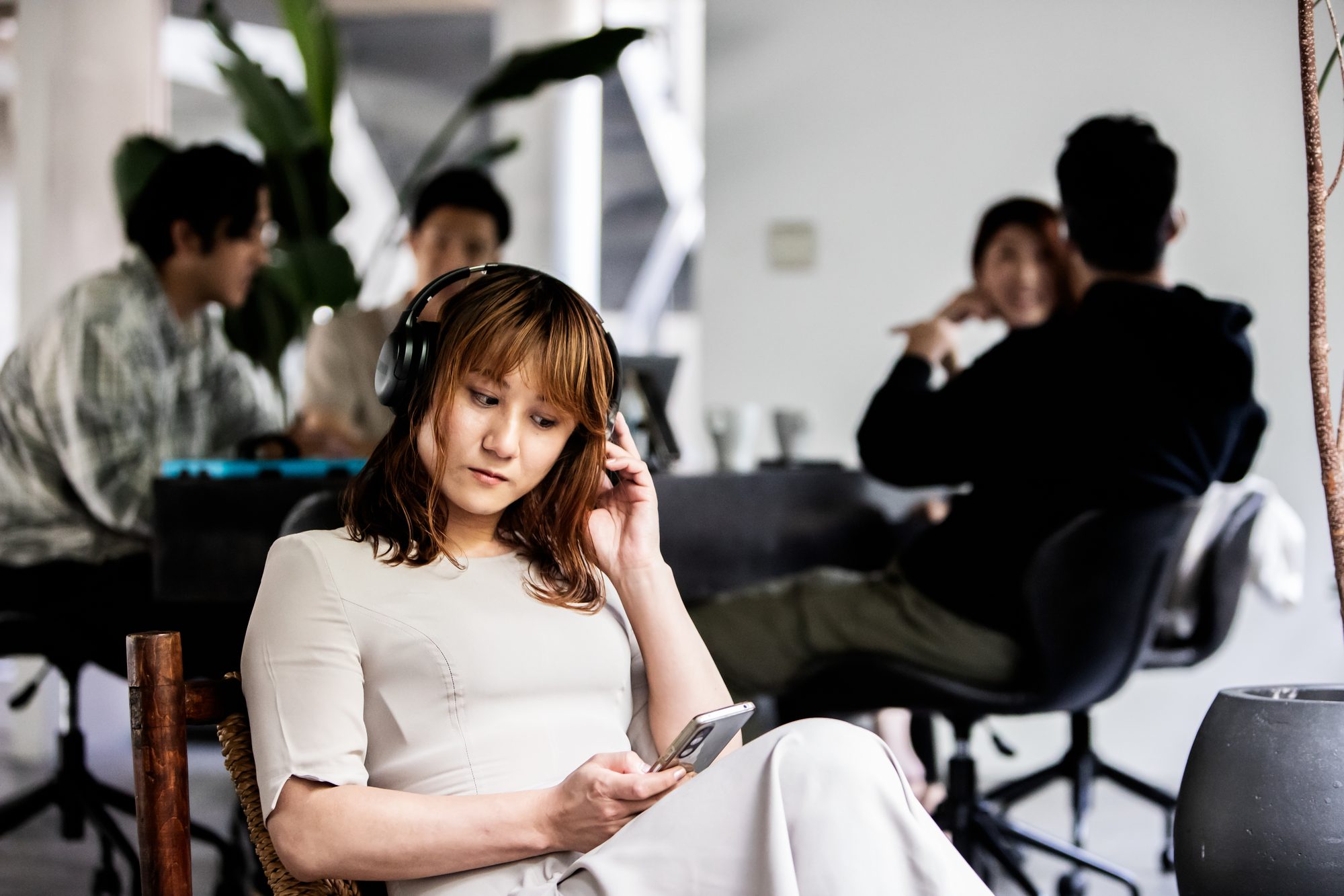 A non-binary person relaxing in the office listening to music.
