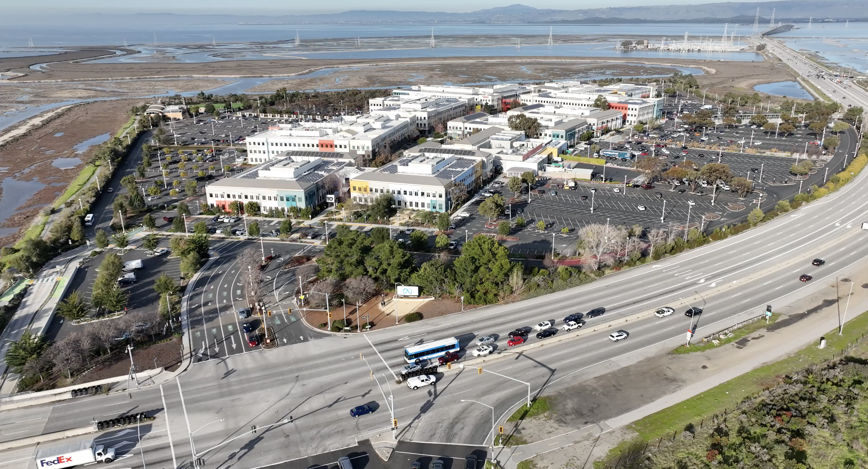 Aerial view of a large corporate campus with office buildings, parking lots, and wetlands nearby.