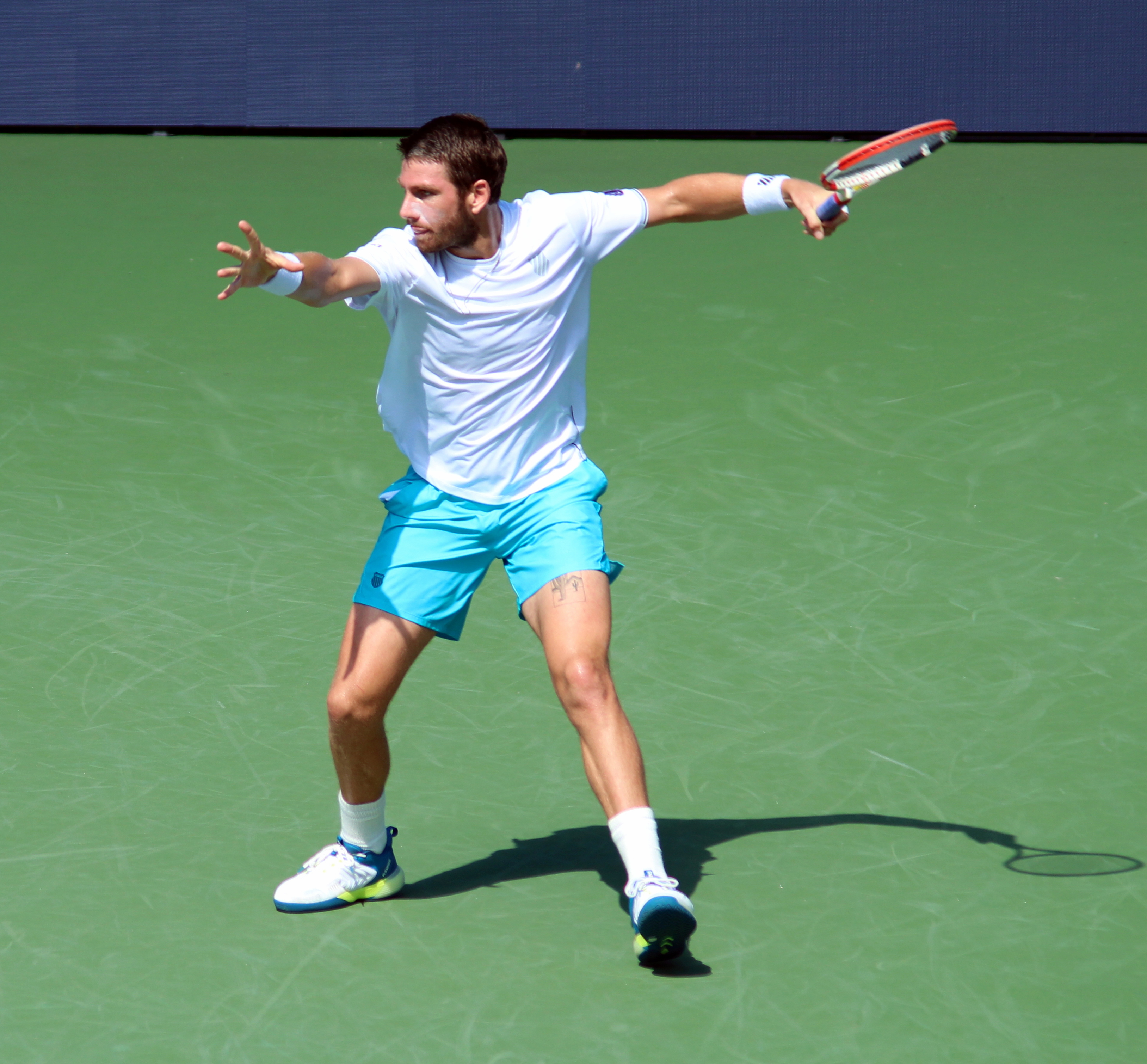 Male tennis player mid-swing hitting a forehand on a hard court