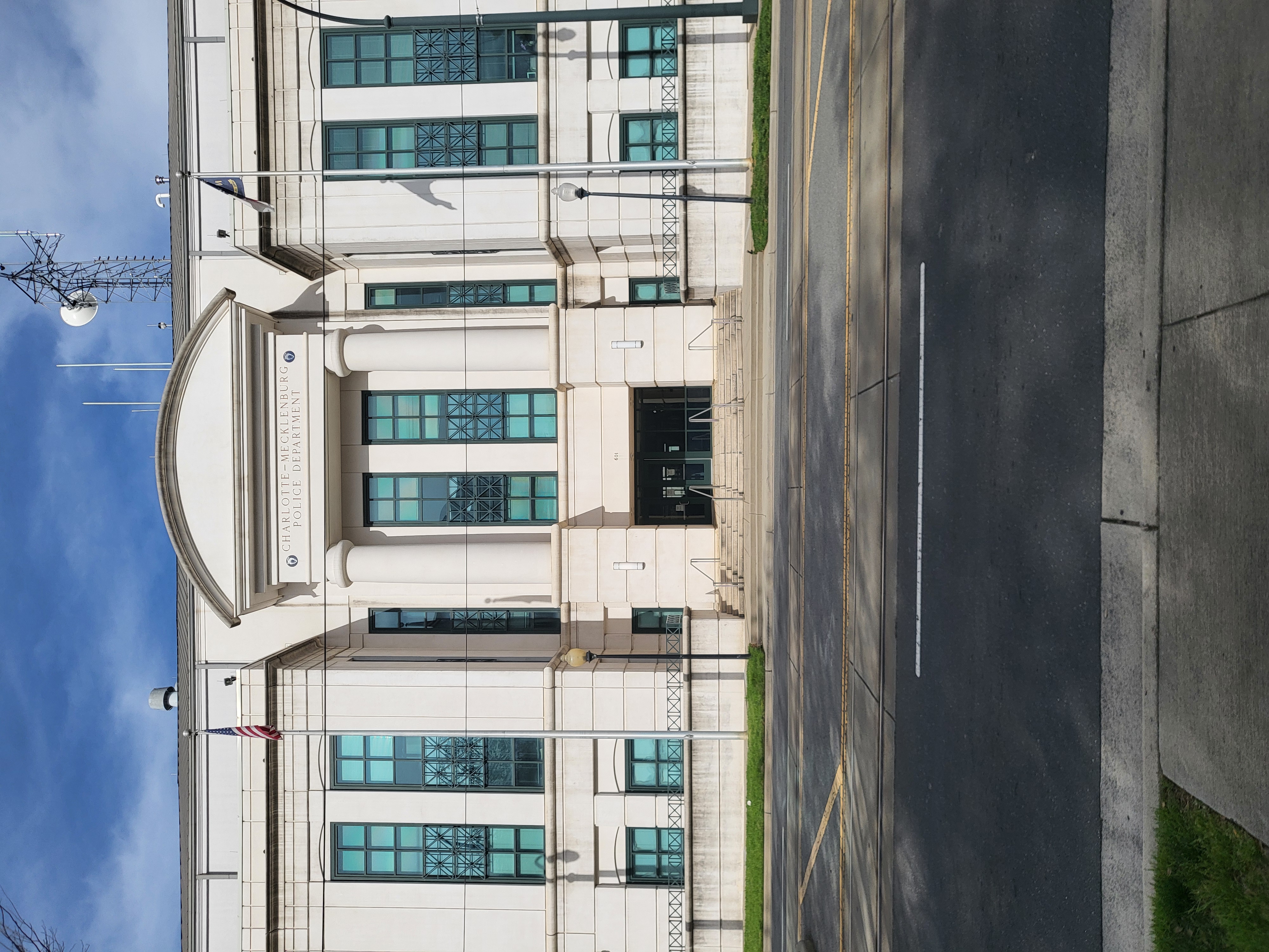 Neoclassical exterior of the Charlotte-Mecklenburg Police Department headquarters building with two flags flanking the entrance.