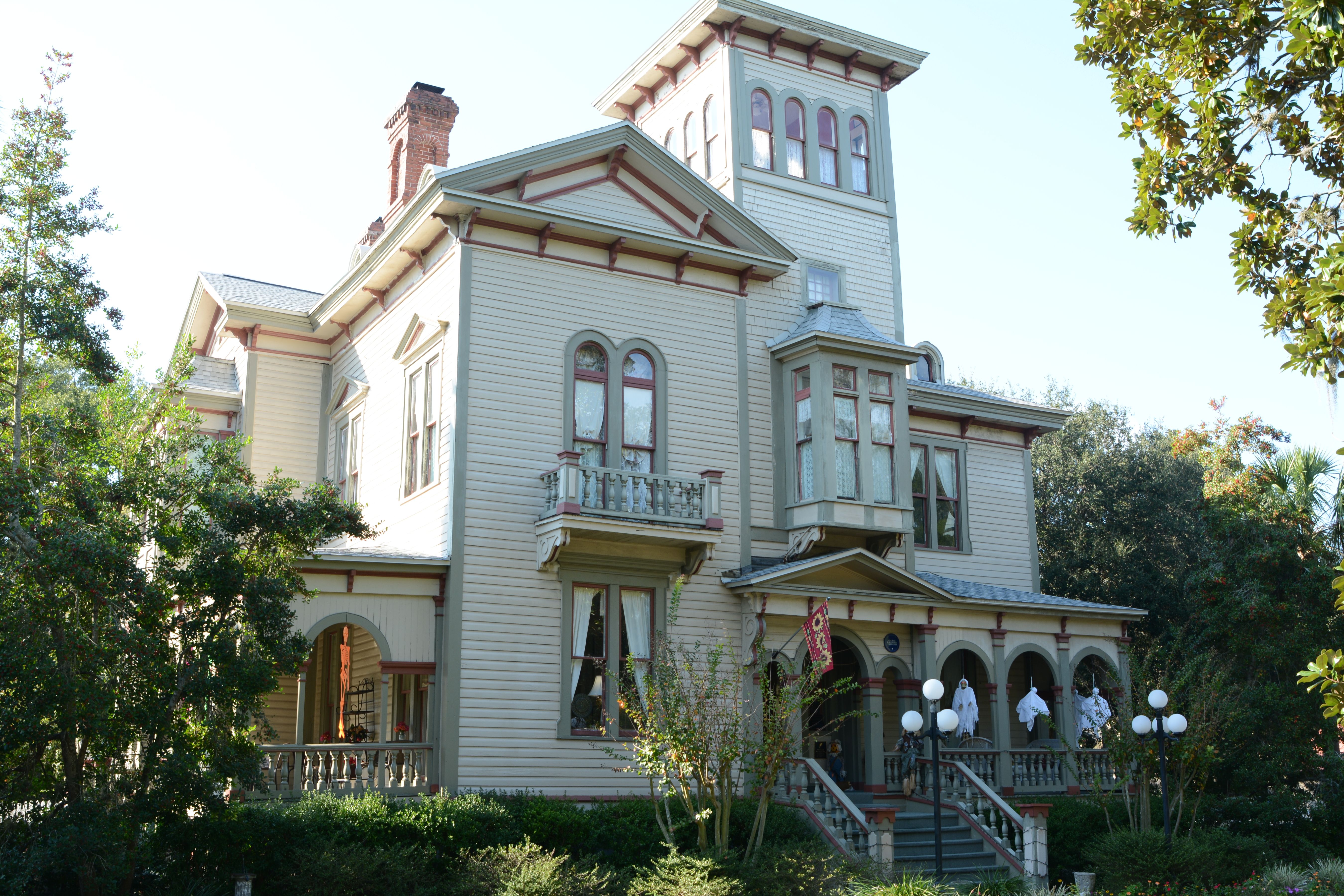 Large Victorian house with tower, wraparound porch, and ornate woodwork